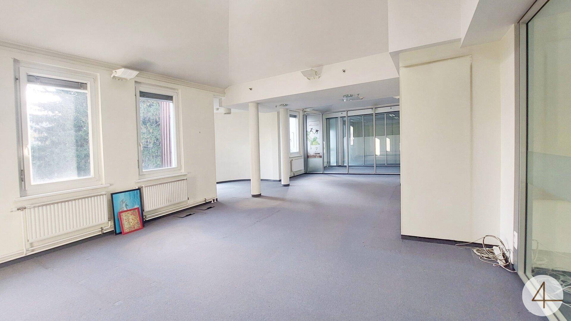Heller Bürobereich mit Teppichboden und mehreren Fenstern, ideal für flexible Arbeitsplatzgestaltung.