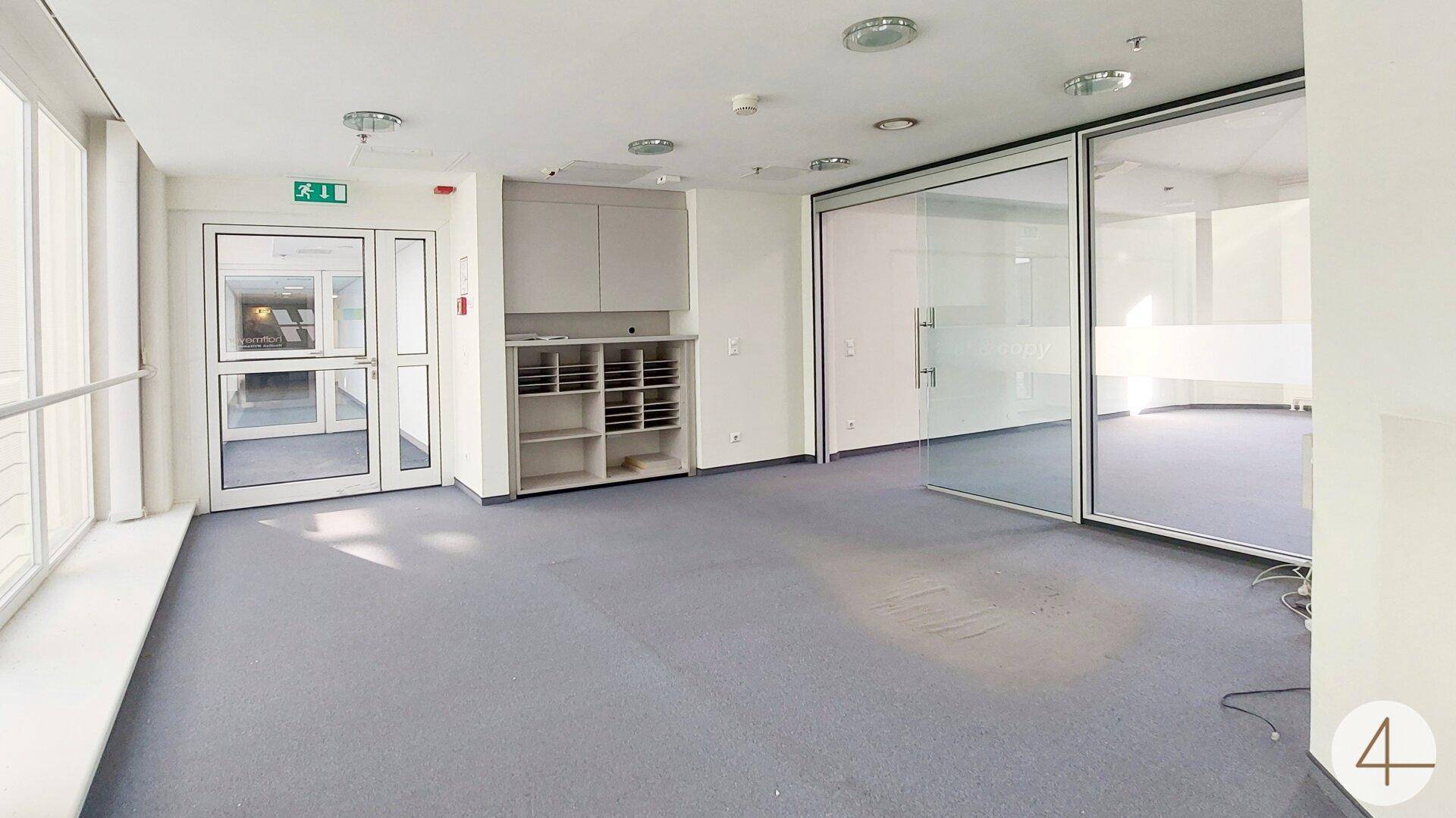 Eingangsbereich eines Büros mit großen Glasfenstern, Schiebetüren und praktischem Stauraum.