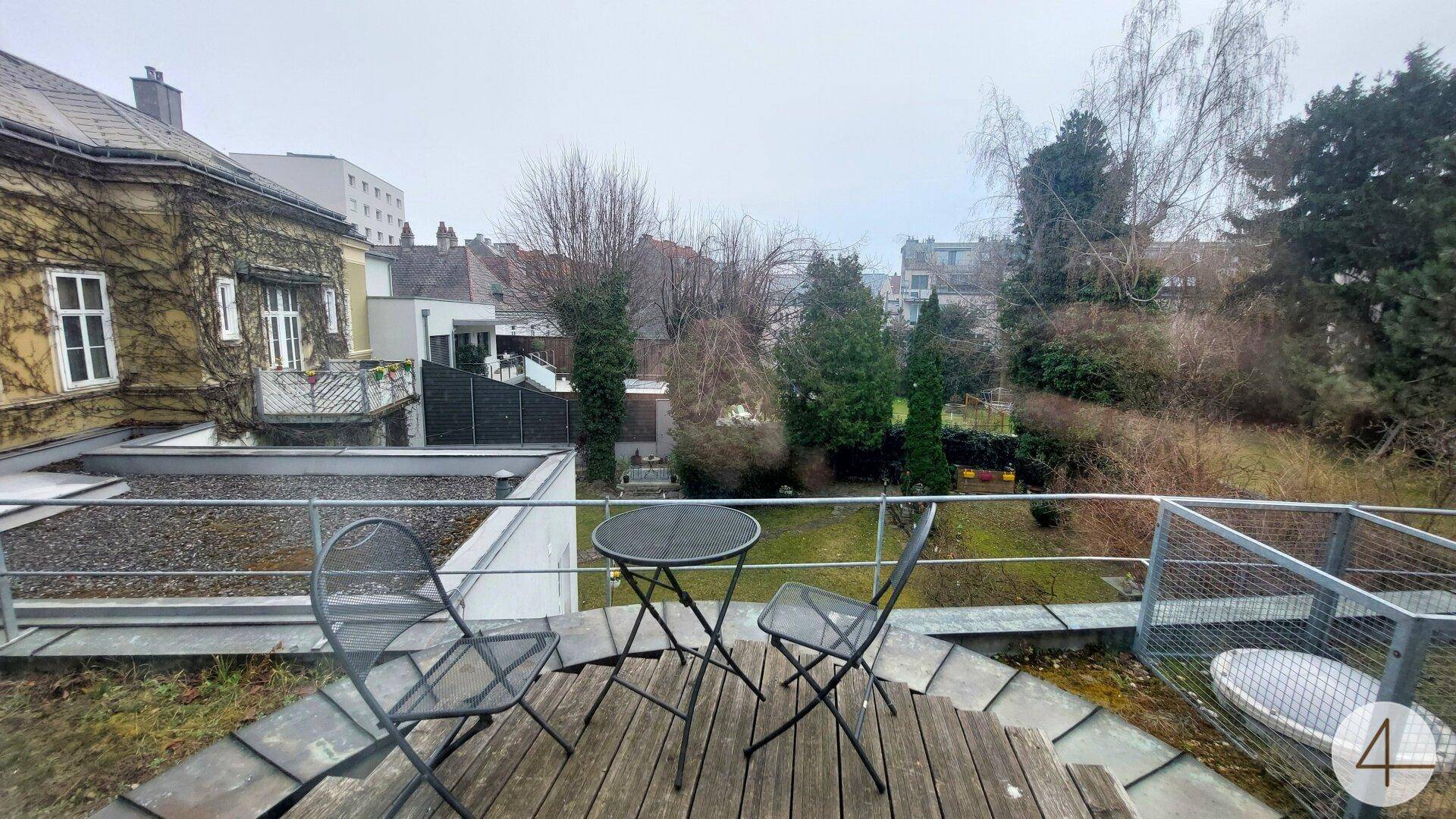 Kleine Terrasse mit Holzboden und Metallmöbeln, bietet einen Blick auf den Garten und die Umgebung.
