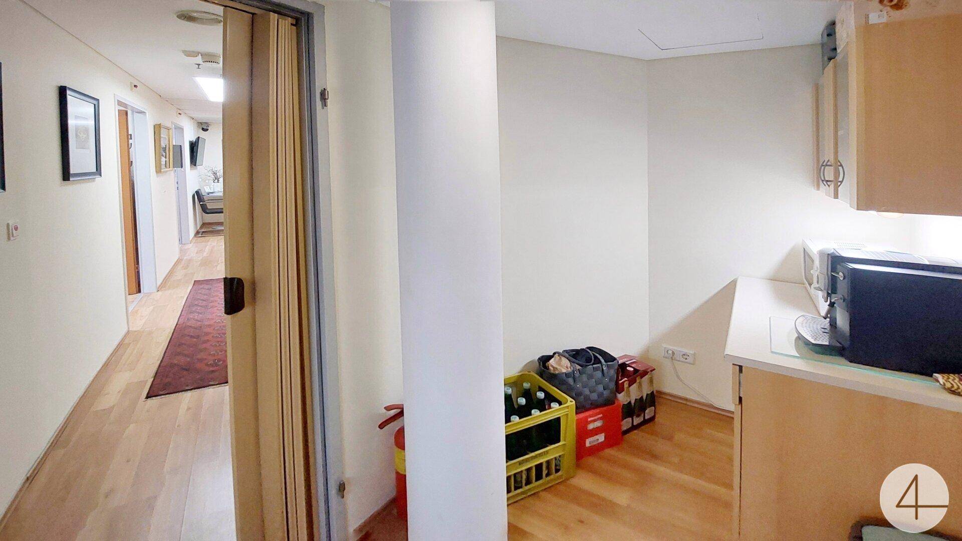 Kleiner Küchenbereich mit Mikrowelle und Stauraum, angrenzend an einen hellen Flur.