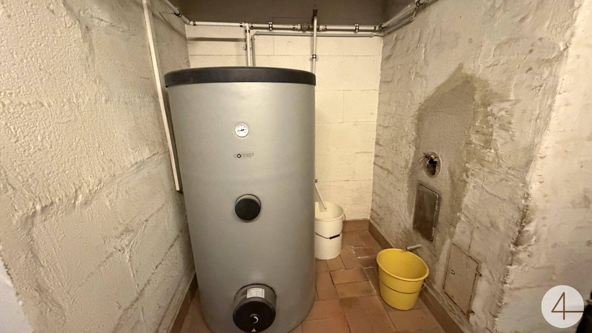 Kellerraum mit großem Warmwasserspeicher und unverputzten Wänden.