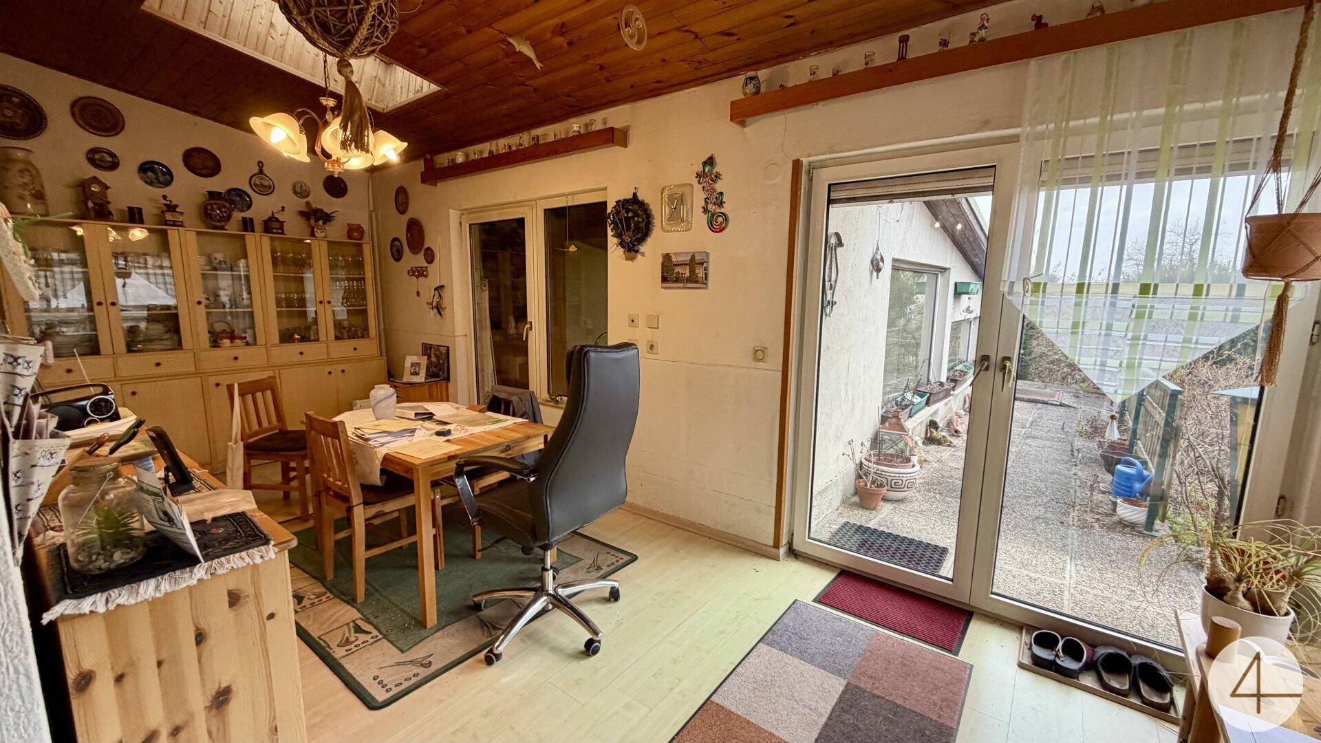 Gemütlicher Essbereich mit Holzdecke, Vitrinen und direktem Zugang zum Garten.