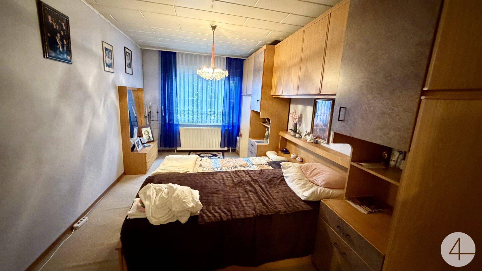 Schlafzimmer mit Doppelbett, Holzschränken und blauen Vorhängen, im traditionellen Stil.