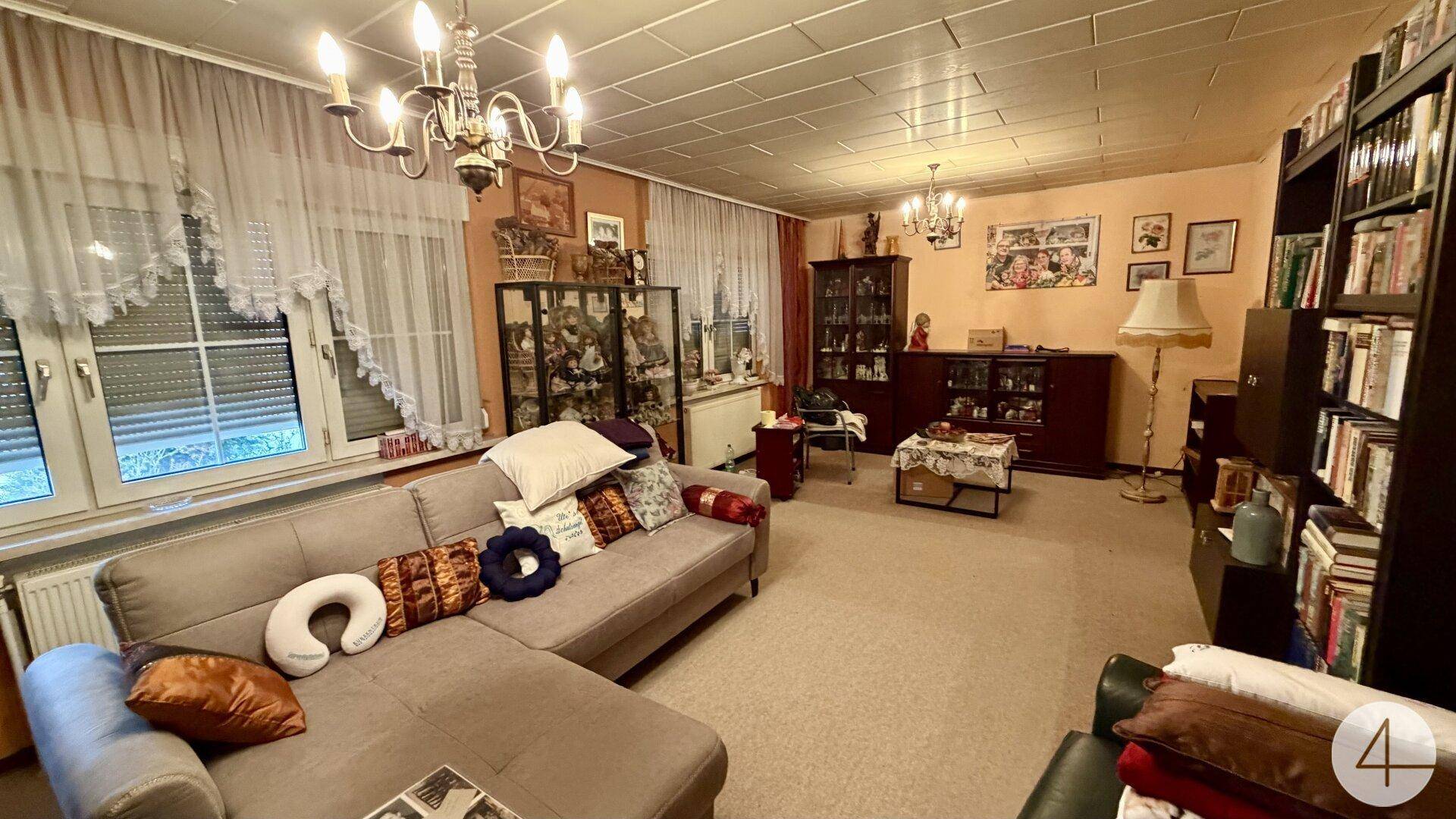 Geräumiges Wohnzimmer mit beigem Sofa, Bücherregalen und klassischer Einrichtung.