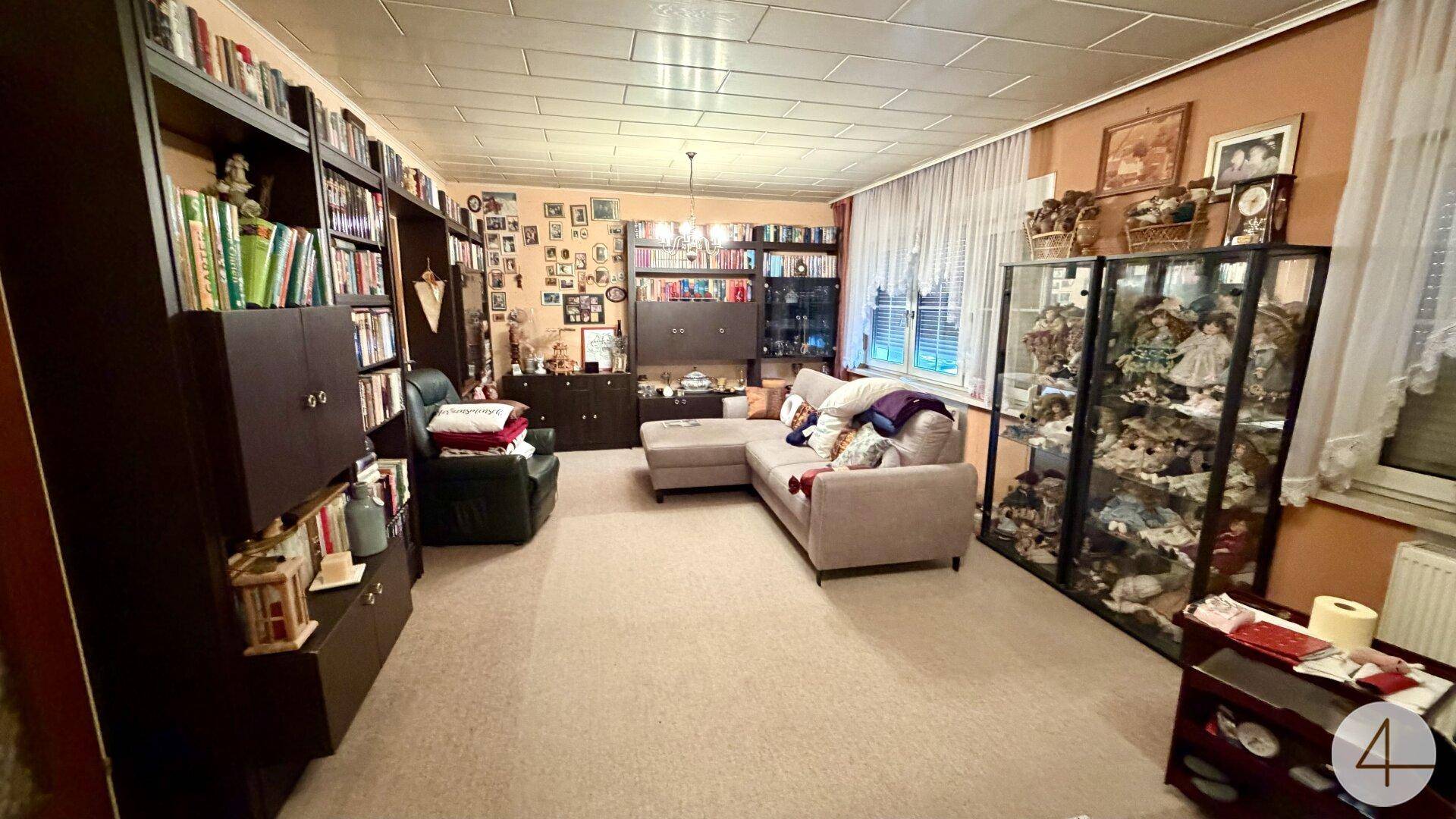 Weiterer Blick ins Wohnzimmer mit umfangreichen Bücherregalen und gemütlicher Sitzecke.
