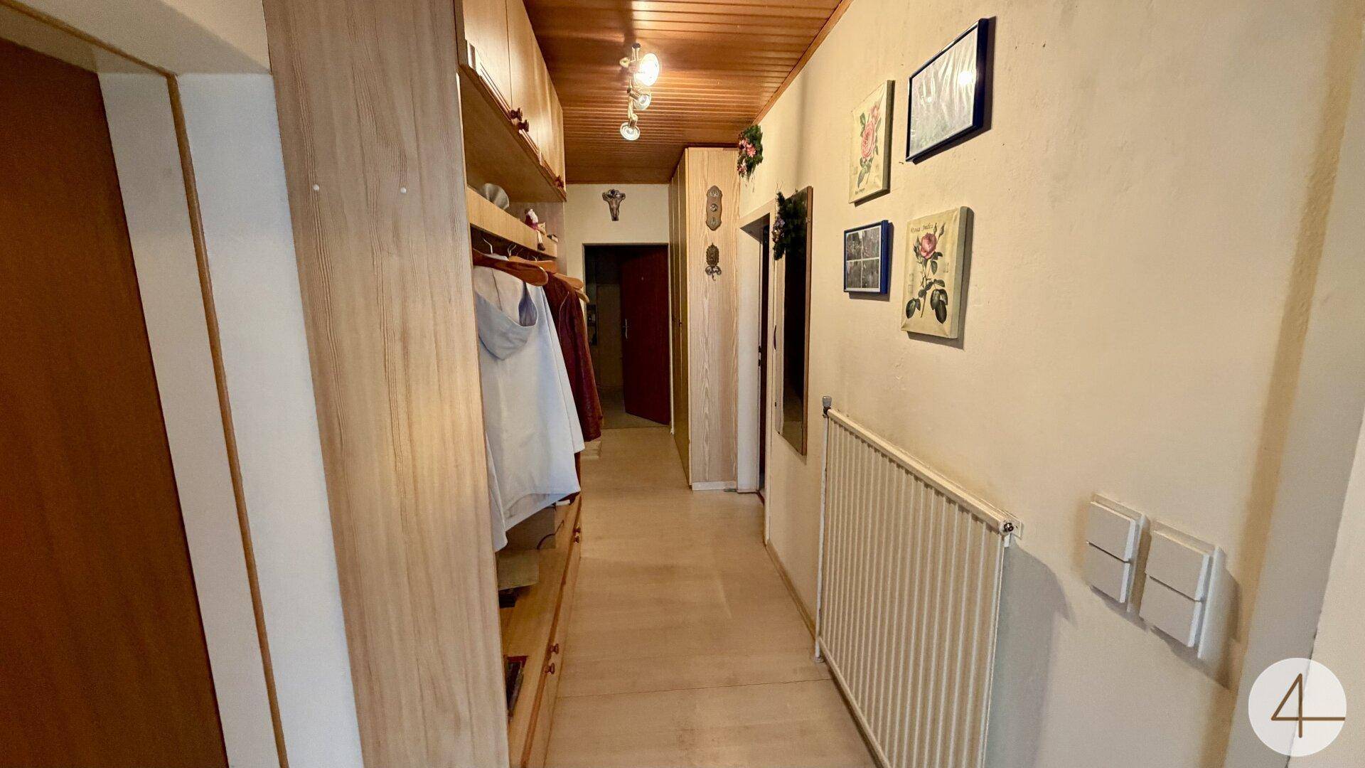 Flur mit Holzdecke, integrierten Schränken und Heizkörper.
