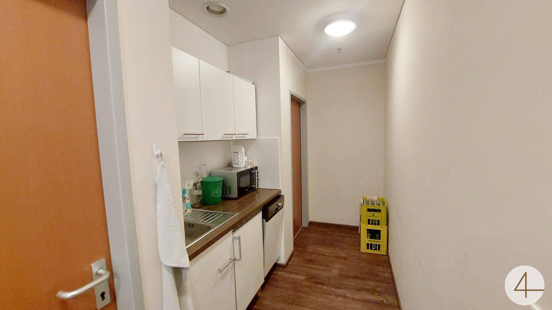 Kompakte Küchenzeile mit Spülbecken, Mikrowelle und Stauraum, ideal für eine schnelle Pause.