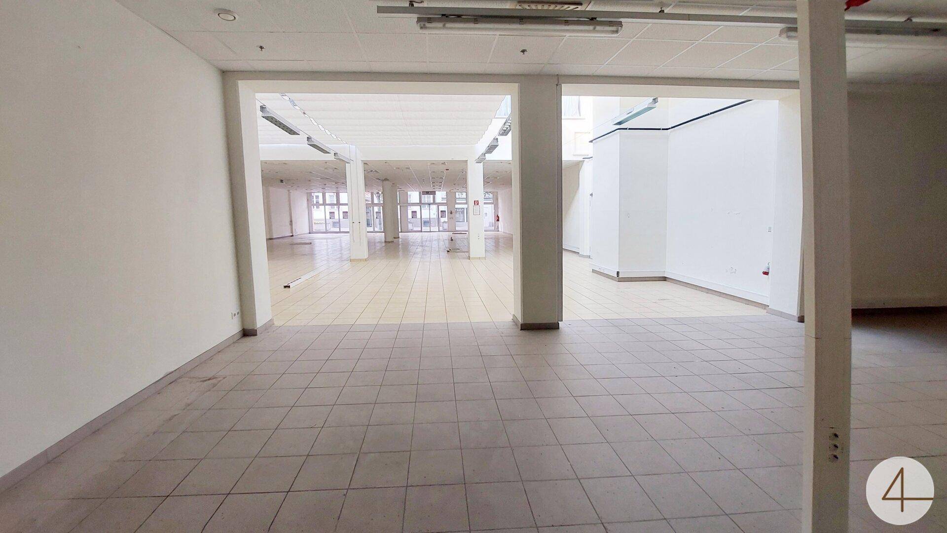 Weitläufiger Gewerberaum mit heller Fliesenfläche und viel Tageslicht durch die Fensterfront, ideal für Geschäfte.