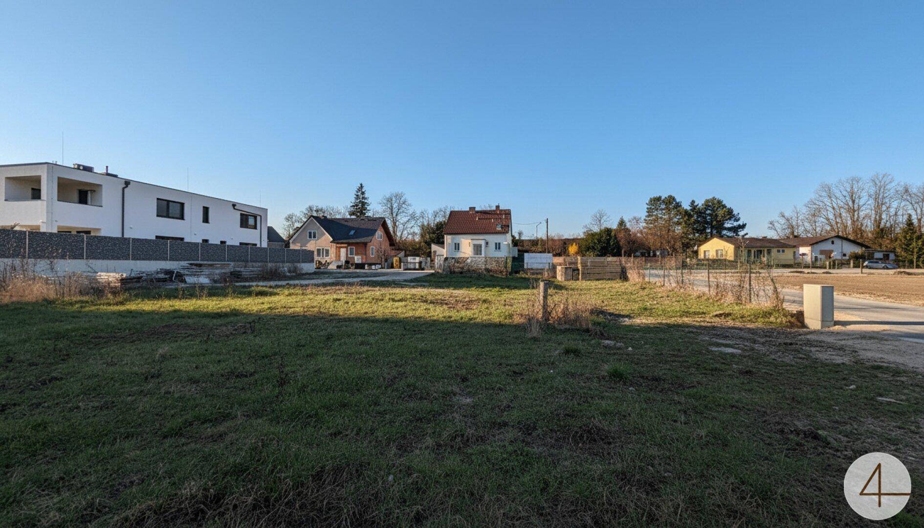 Freies Baugrundstück mit Blick auf moderne und traditionelle Gebäude in der Umgebung.