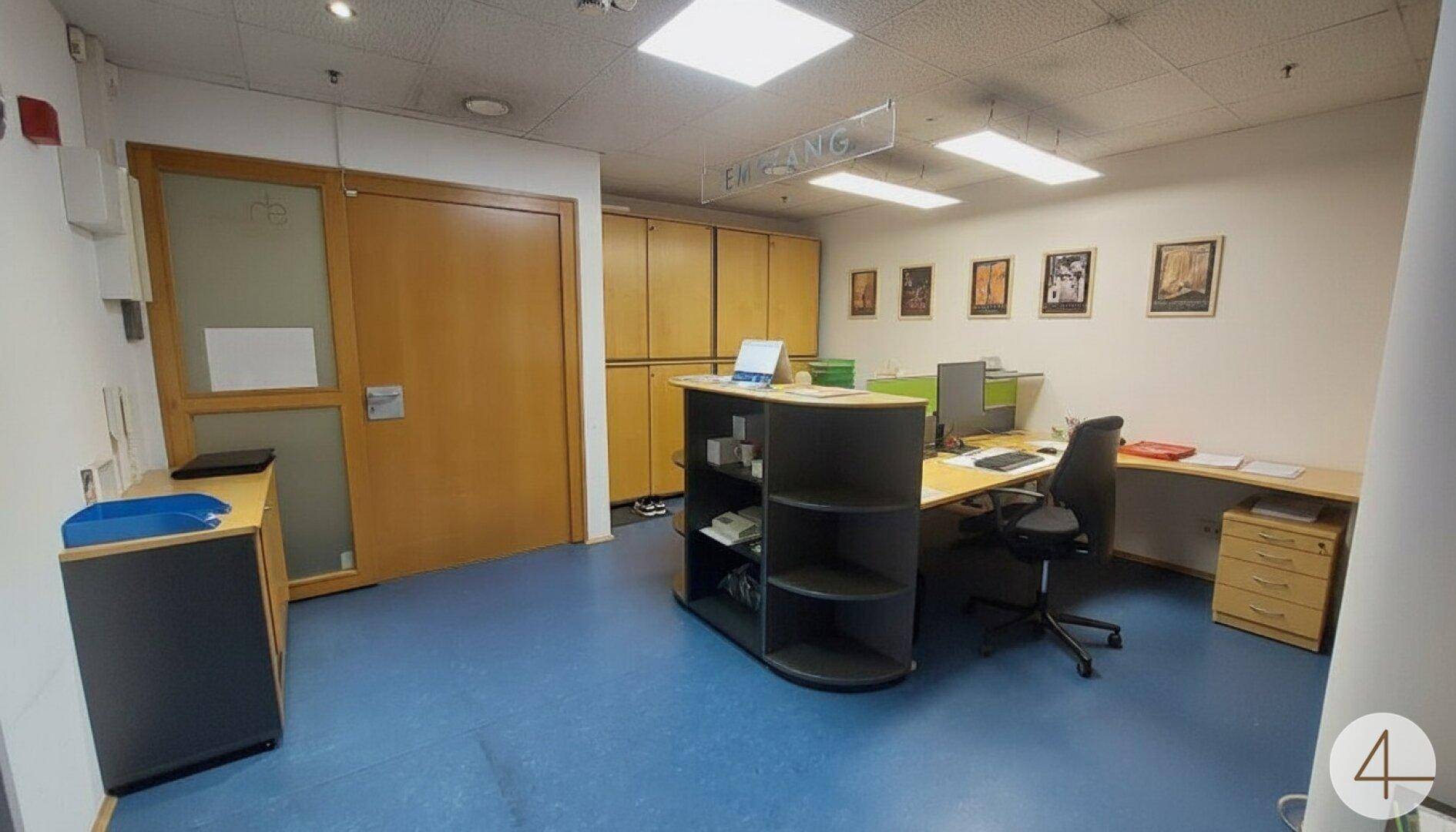 Empfangsbereich mit Schreibtisch, Bürostuhl und Holzschränken, der einen funktionalen Arbeitsplatz bietet.