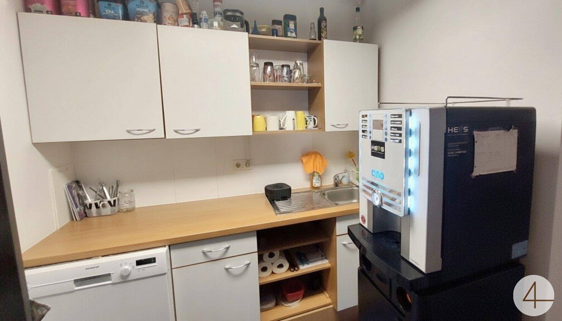 Funktionale Küchenzeile mit Spüle, Geschirrspüler und Kaffeemaschine, ideal für Pausen.