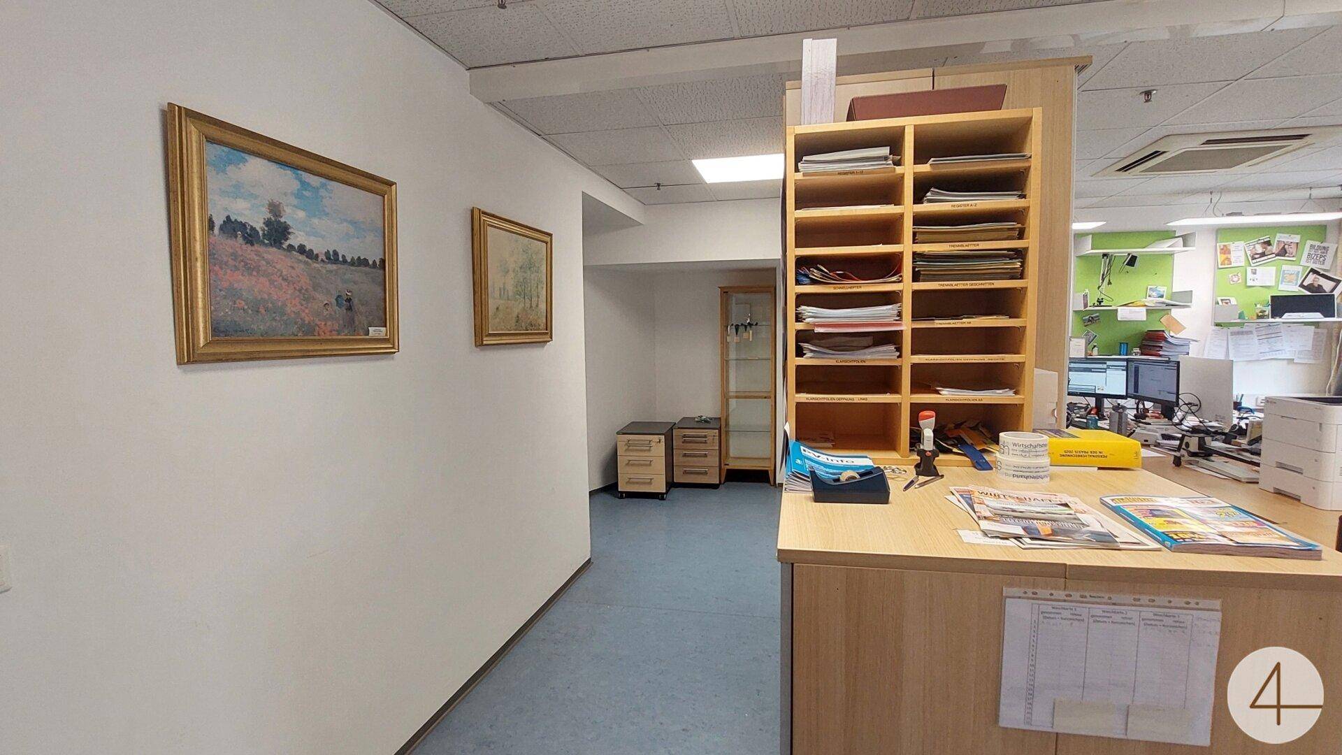 Bürobereich mit Schreibtisch, Regalen und Kunstwerken an der Wand, der eine angenehme Arbeitsatmosphäre schafft.
