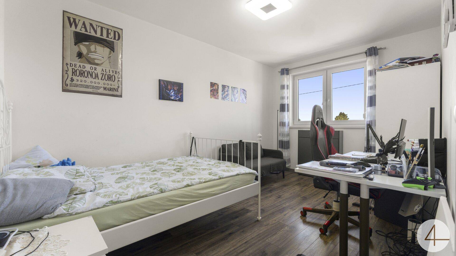 Helles Jugendzimmer mit Holzboden, Einzelbett und Schreibtisch am Fenster.