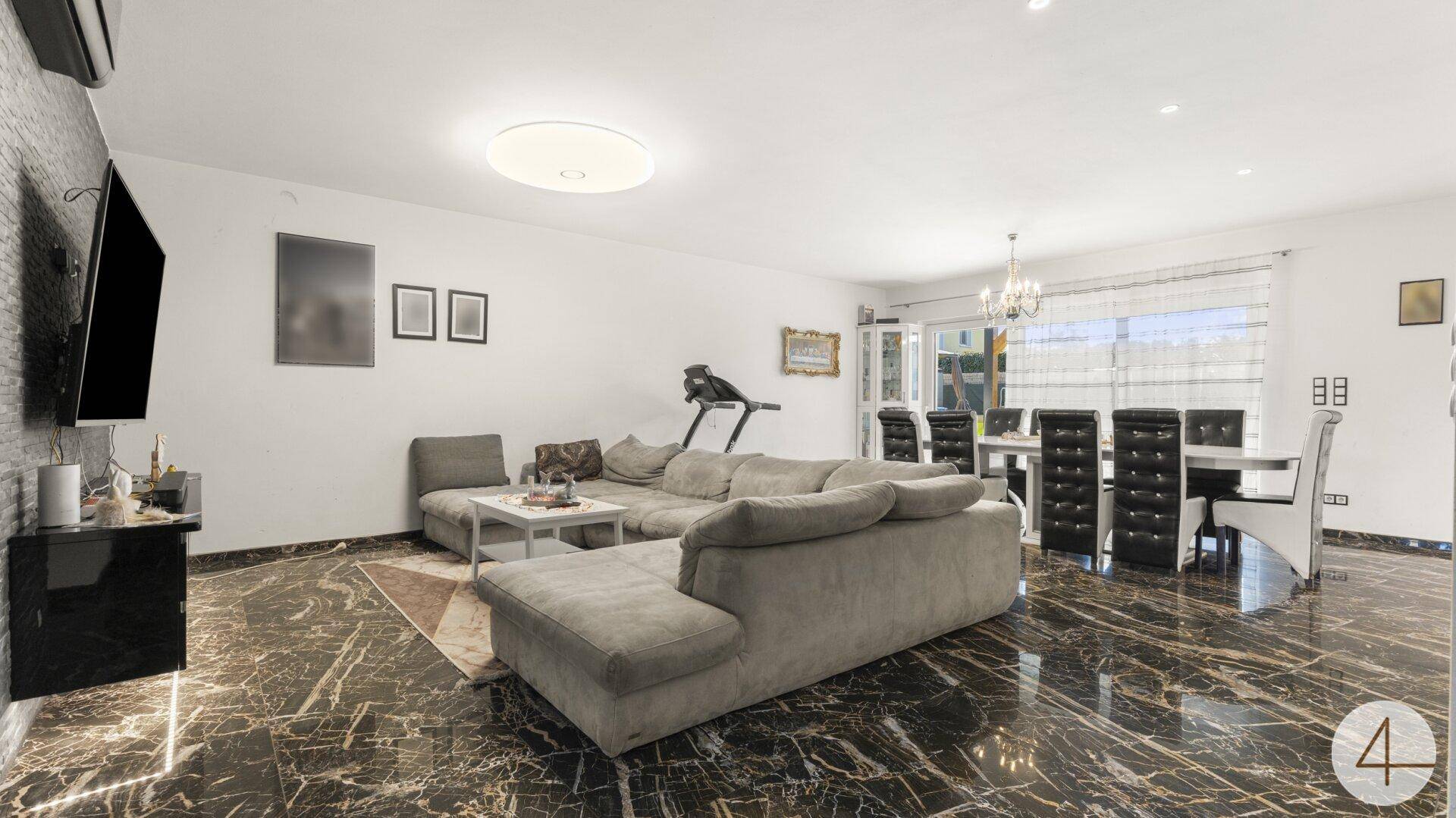 Gemütliches Wohnzimmer mit großem Sofa, Steinwand und dunklem Marmorboden.