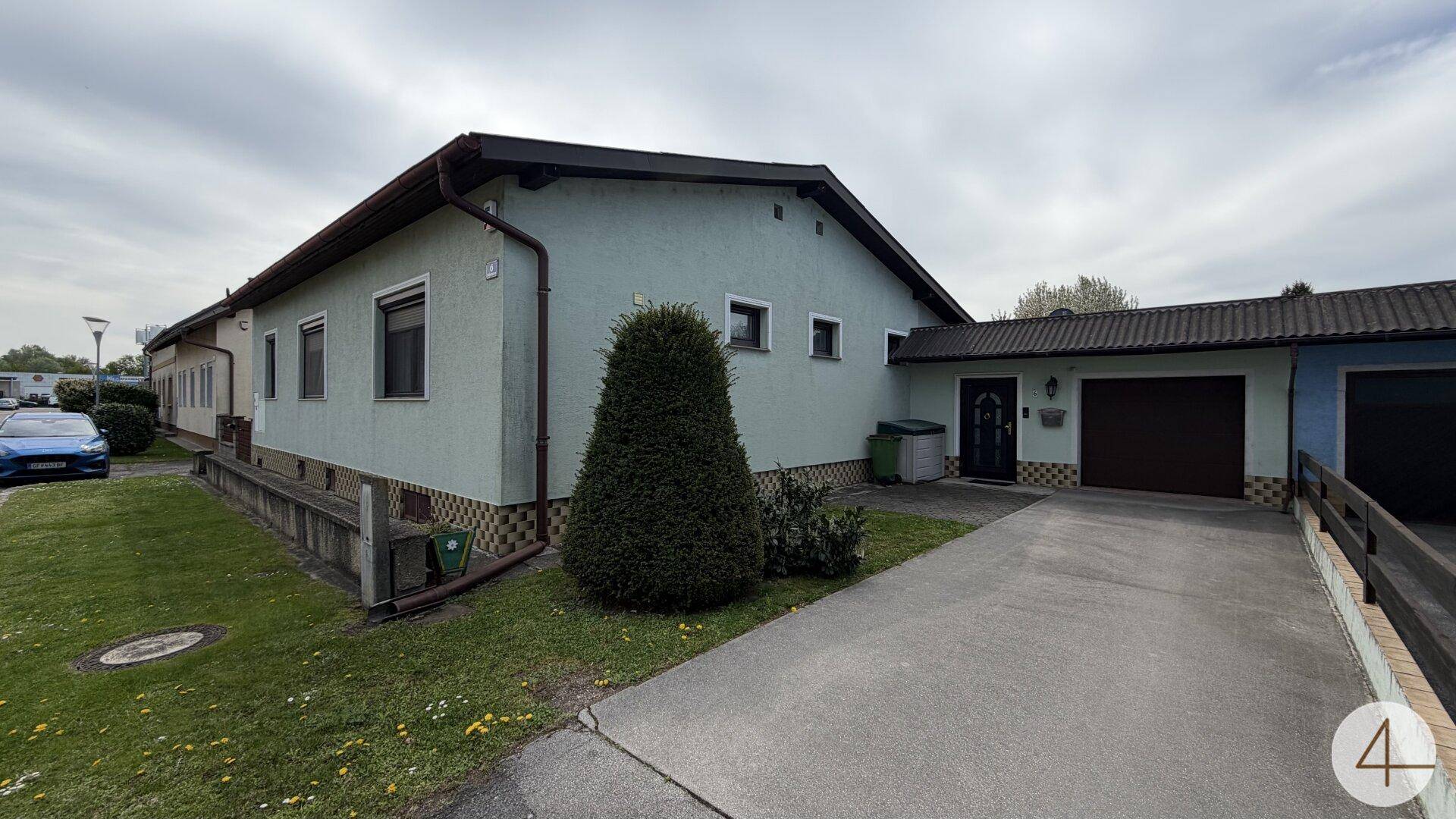 Seitenansicht des Hauses mit einer Einfahrt, Garage und einem kleinen Vorgartenbereich.