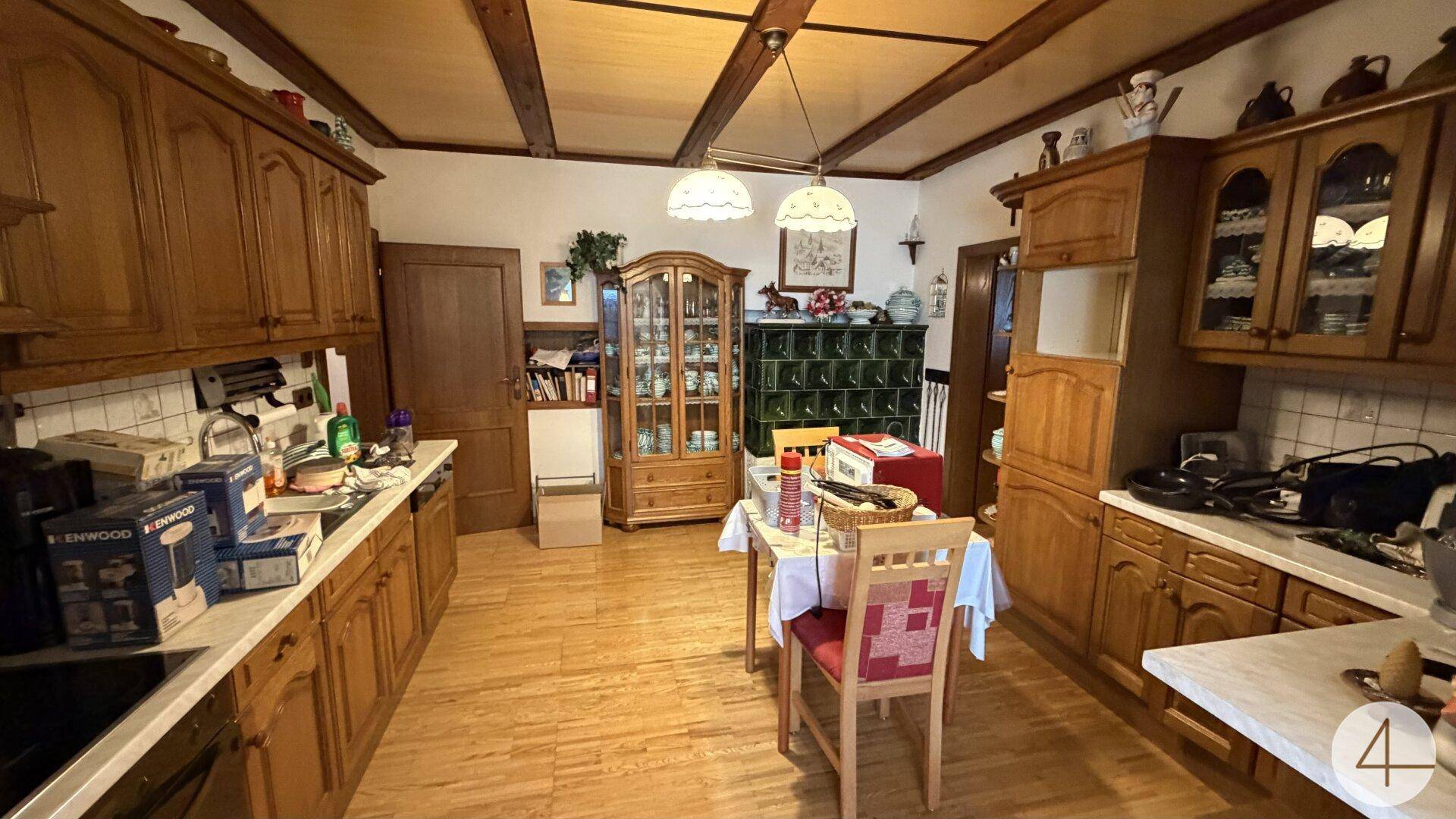 Geräumige Küche im Landhausstil mit Holzeinbauten, Essbereich und einem traditionellen Kachelofen.