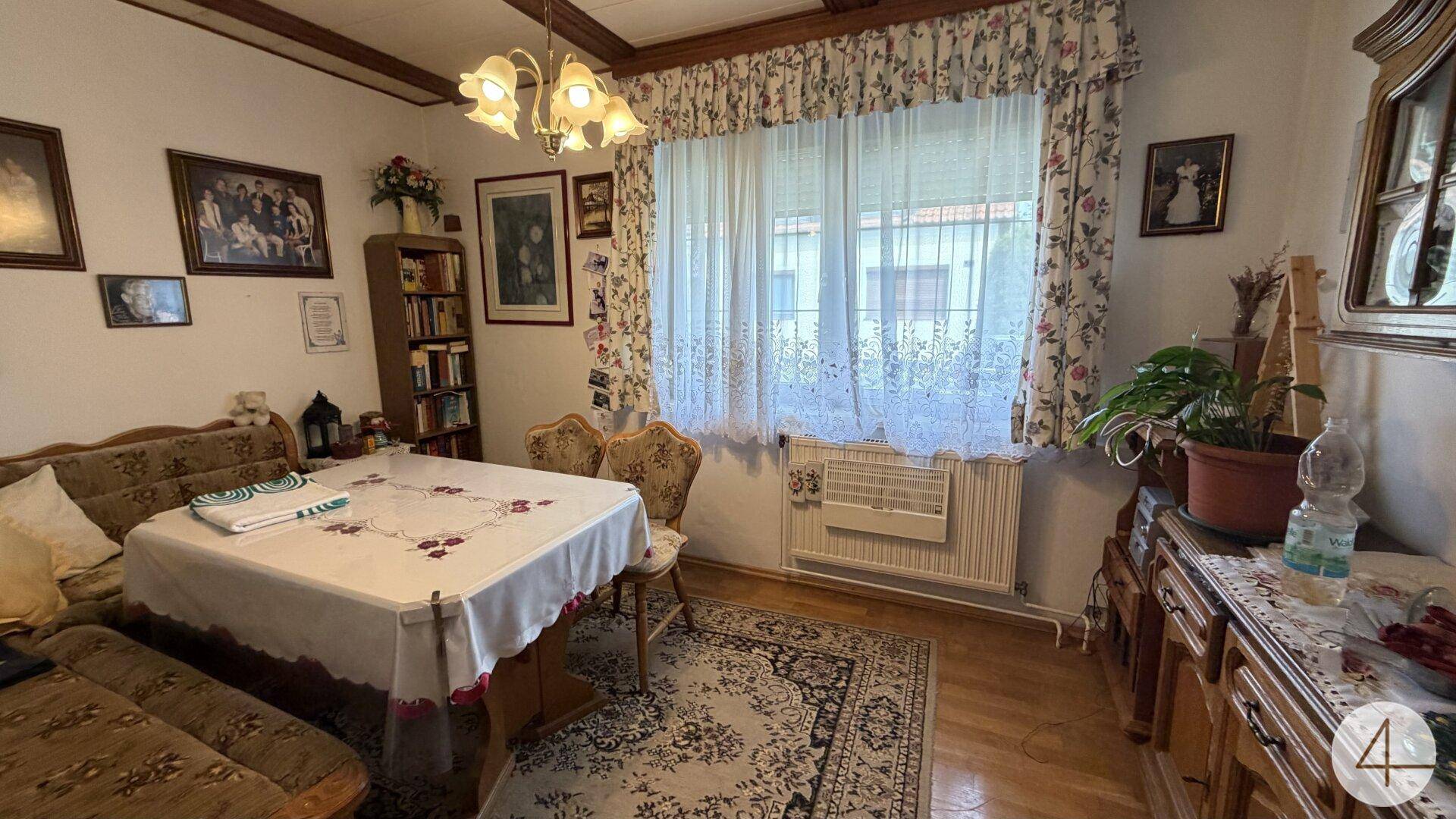 Traditioneller Essbereich mit großem Holztisch, Teppich und Blick in den Garten durch das Fenster.