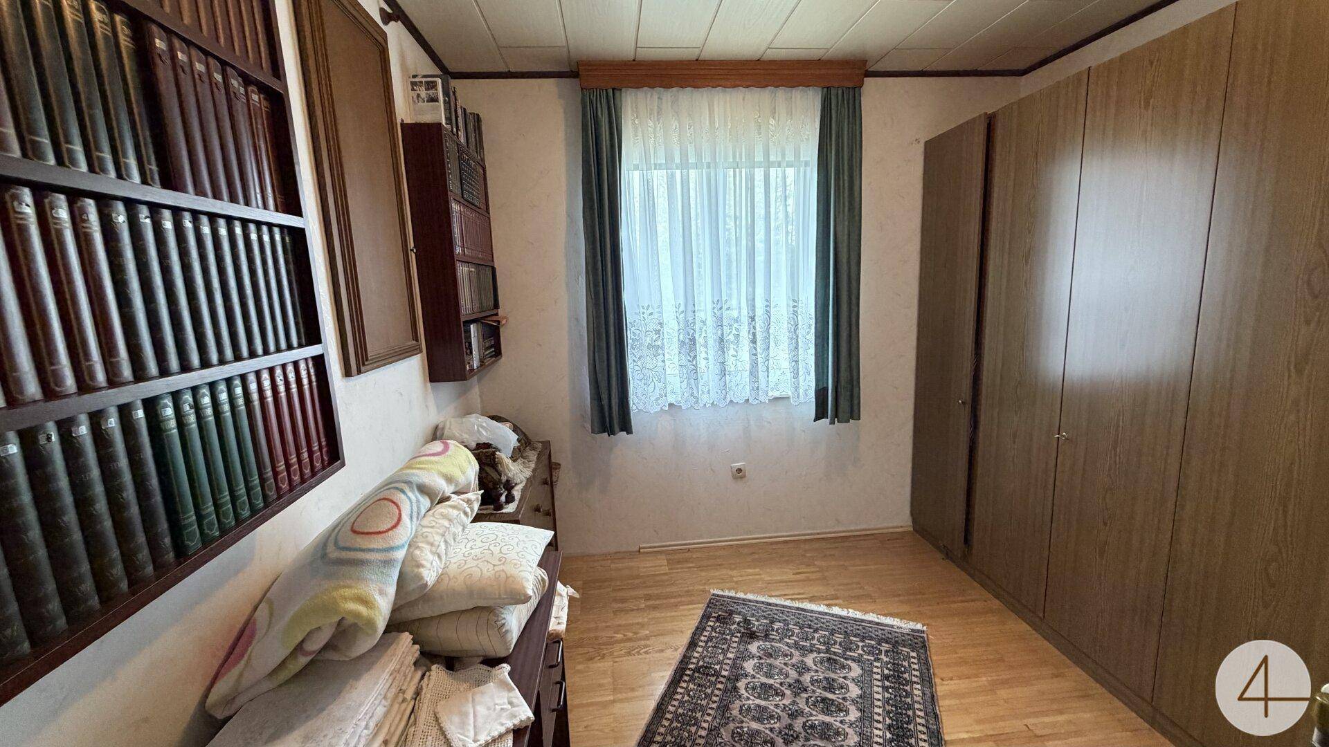 Schlafzimmer mit Holzfußboden, Einbauschränken und einem Fenster mit Blick nach draußen.