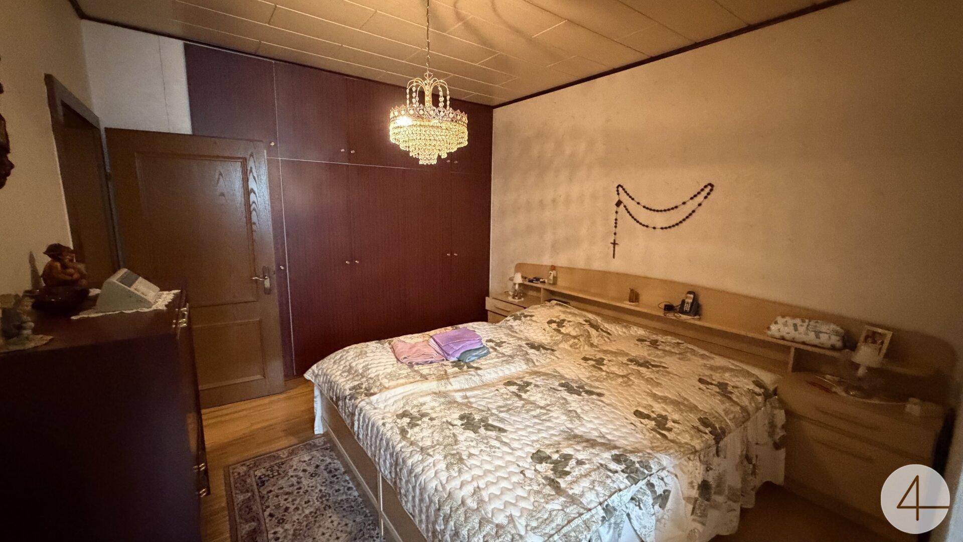 Geräumiges Schlafzimmer mit Doppelbett, Einbauschränken und einem Kronleuchter an der Decke.