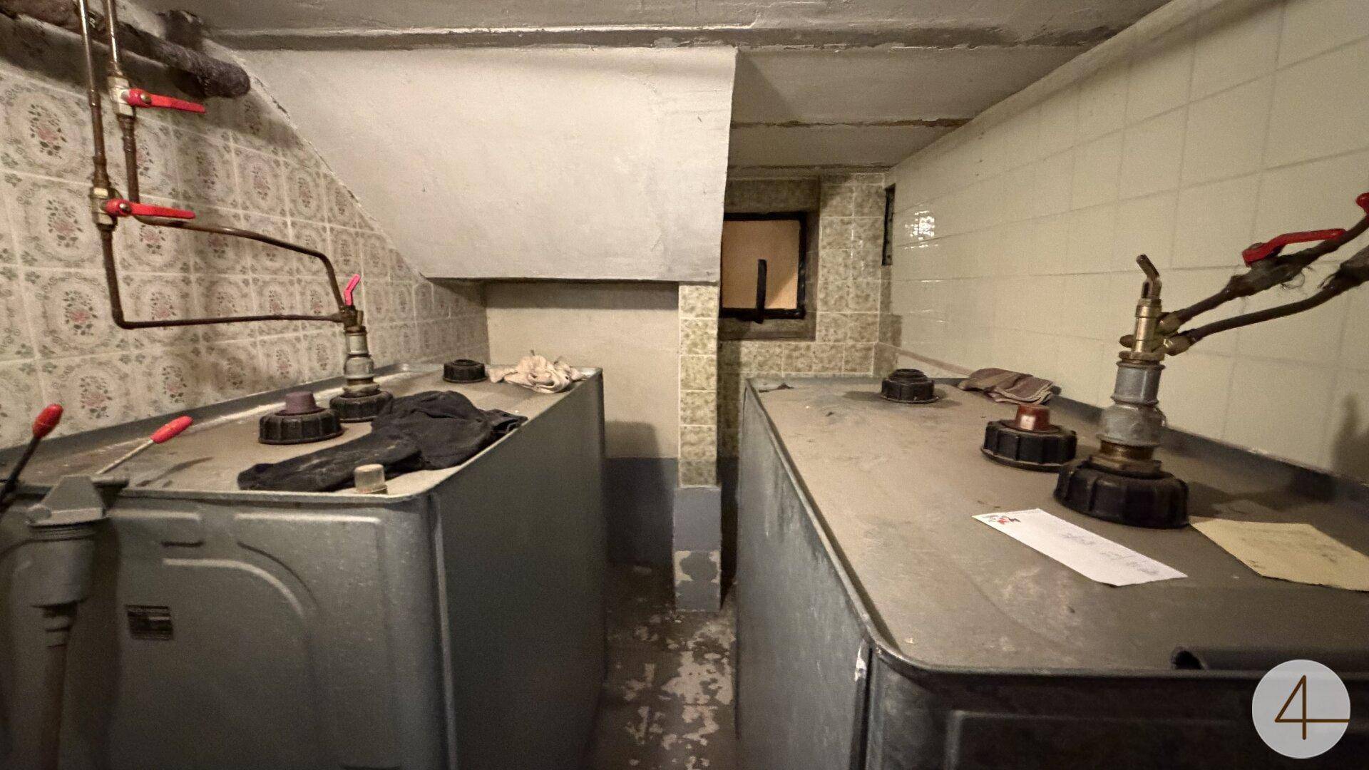 Heizungsraum im Keller mit zwei Öltanks und sichtbaren Rohrleitungen.