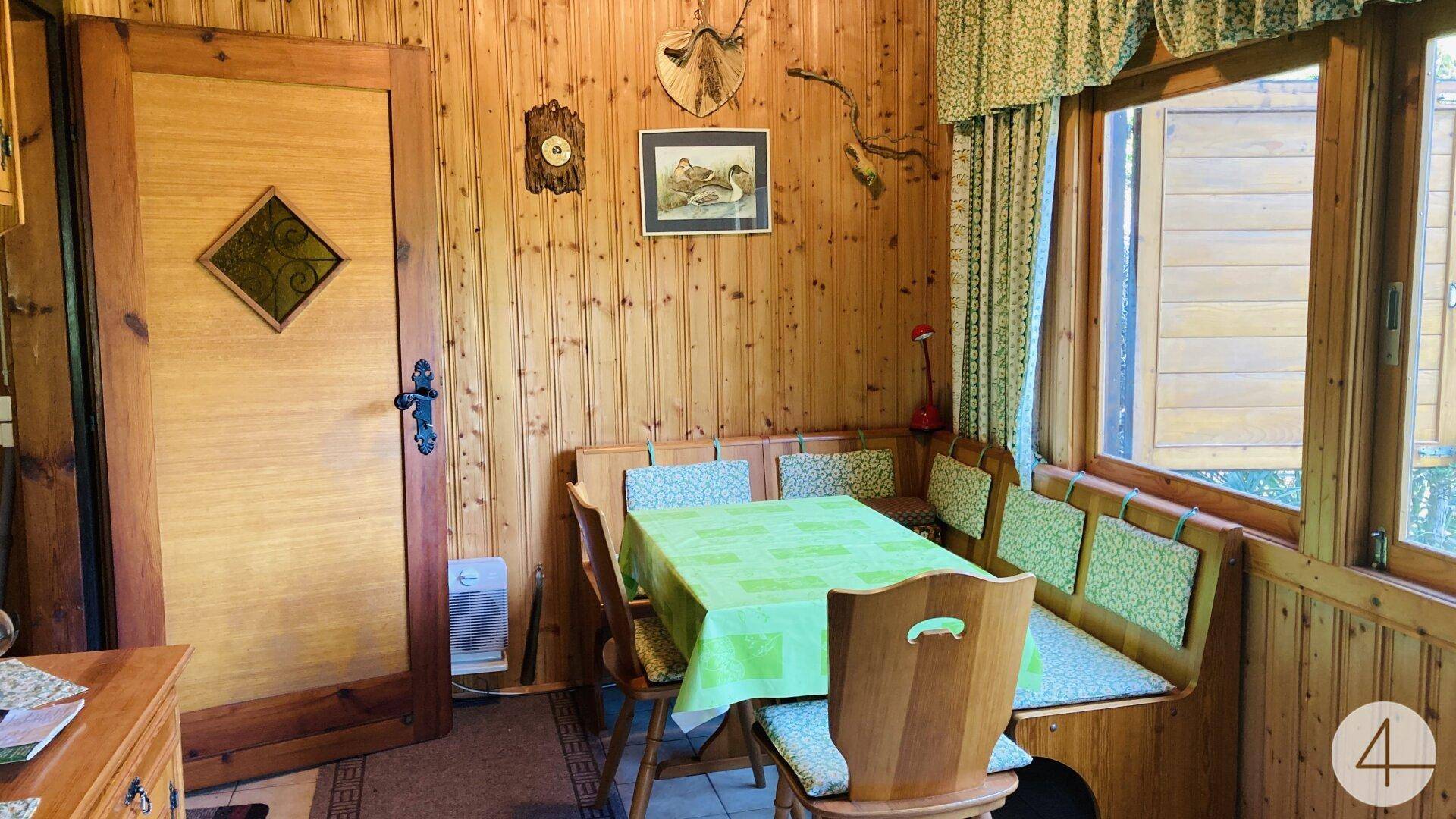 Gemütliche Essecke im alpinen Stil mit Holztäfelung, traditionellen Möbeln und Blick ins Grüne.