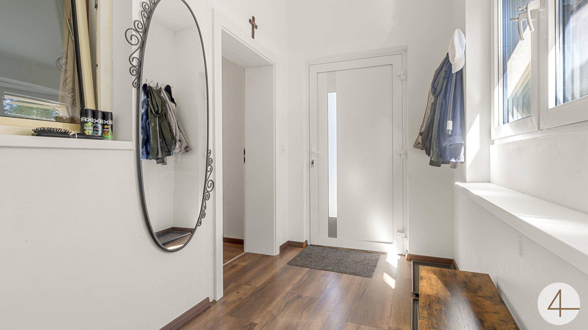 Heller Eingangsbereich mit Garderobe, großem Spiegel und Holzfußboden.