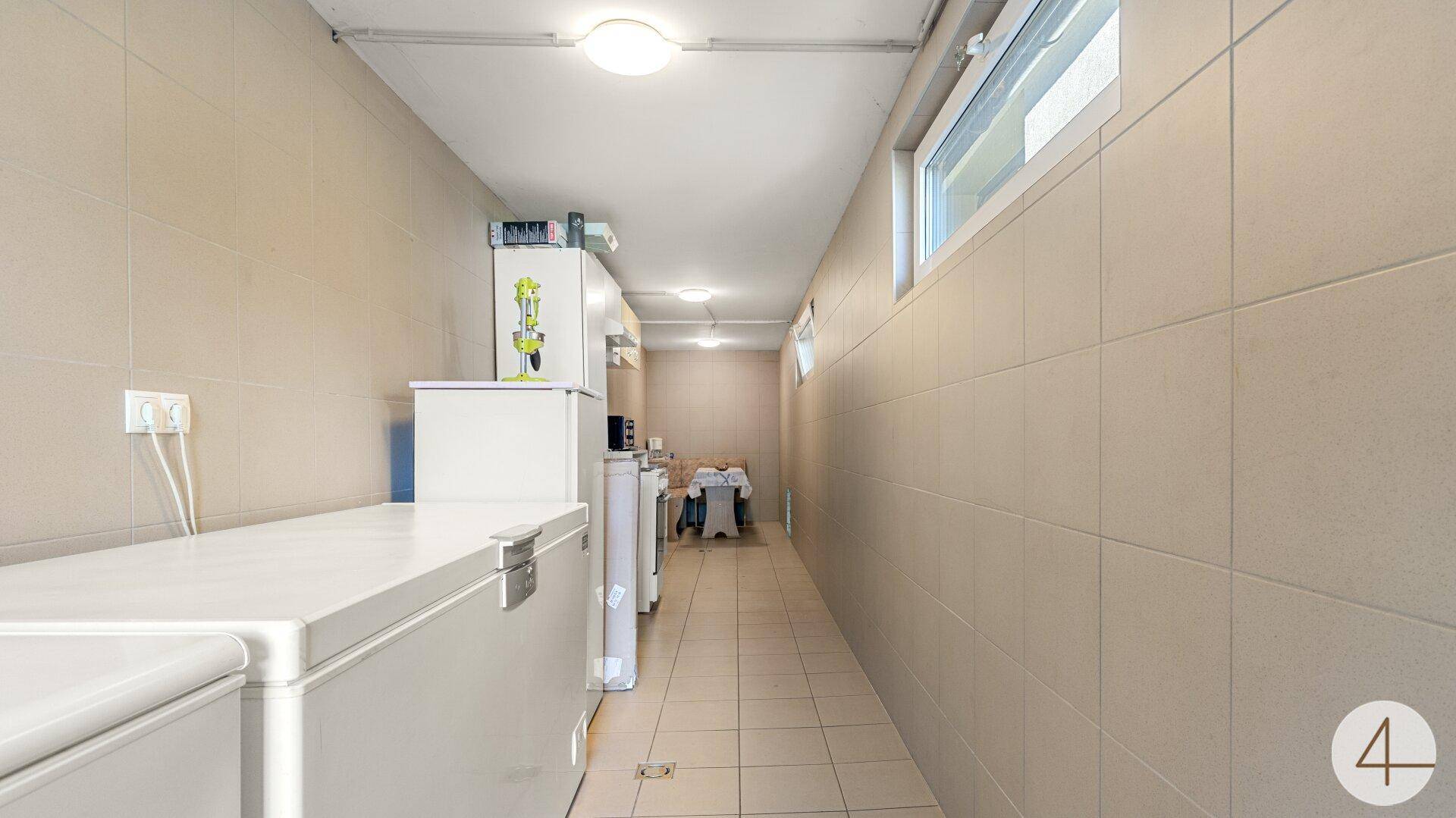 Langer Hauswirtschaftsraum im Untergeschoss mit Fliesenboden und mehreren Gefriertruhen.
