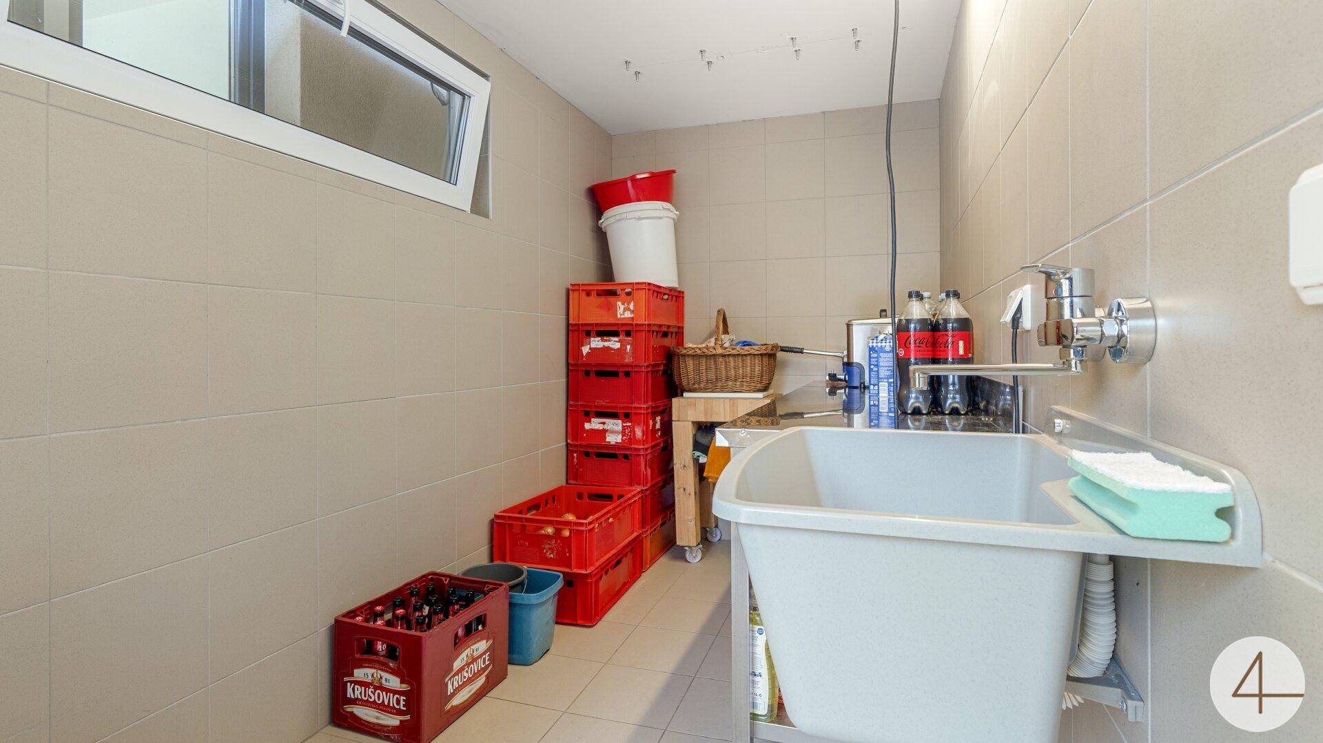 Praktischer Hauswirtschaftsraum im Untergeschoss mit Waschbecken und Stauraum.