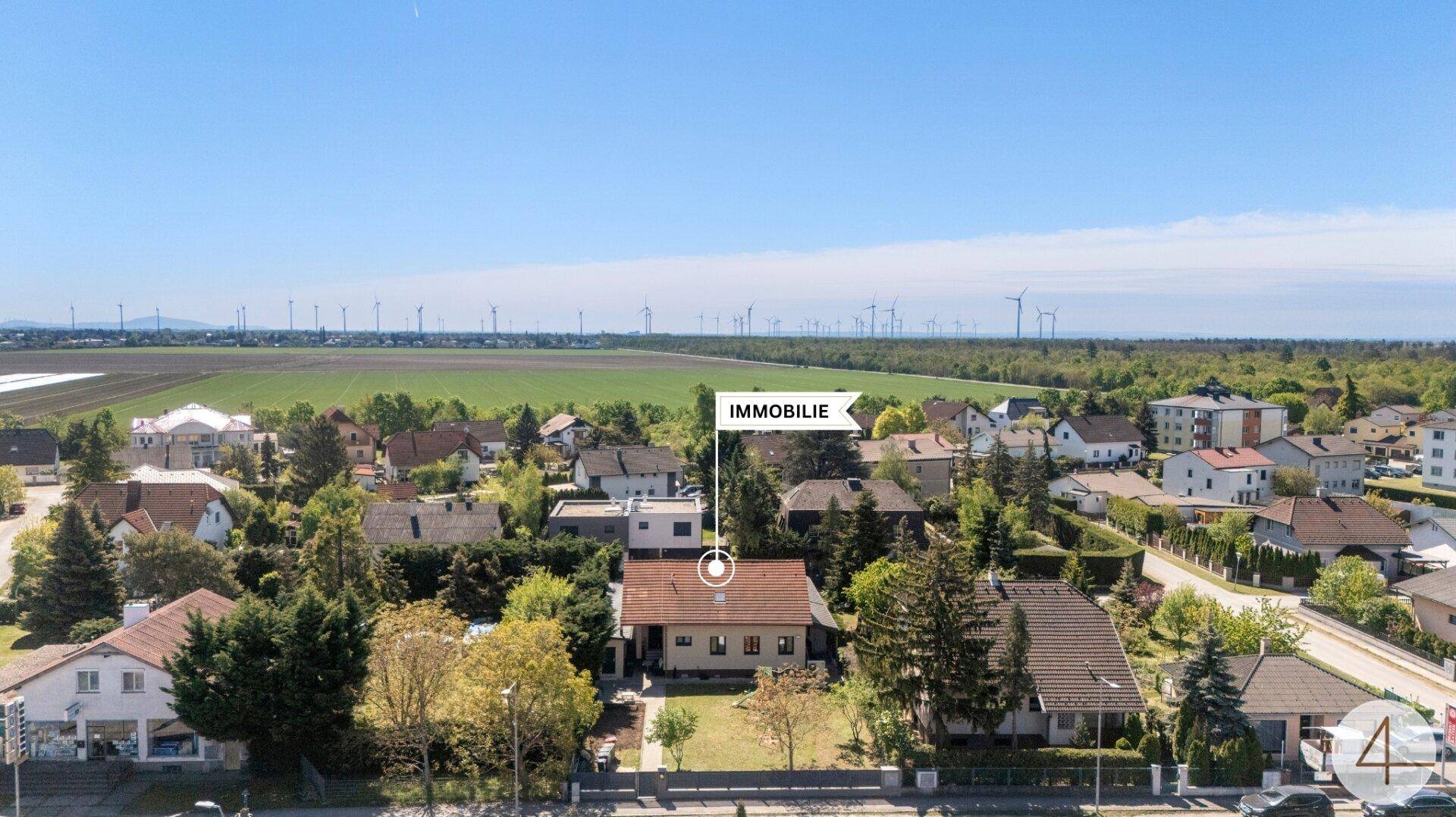 Weitläufige Luftaufnahme der Immobilie mit ländlicher Umgebung und Windkraftanlagen.