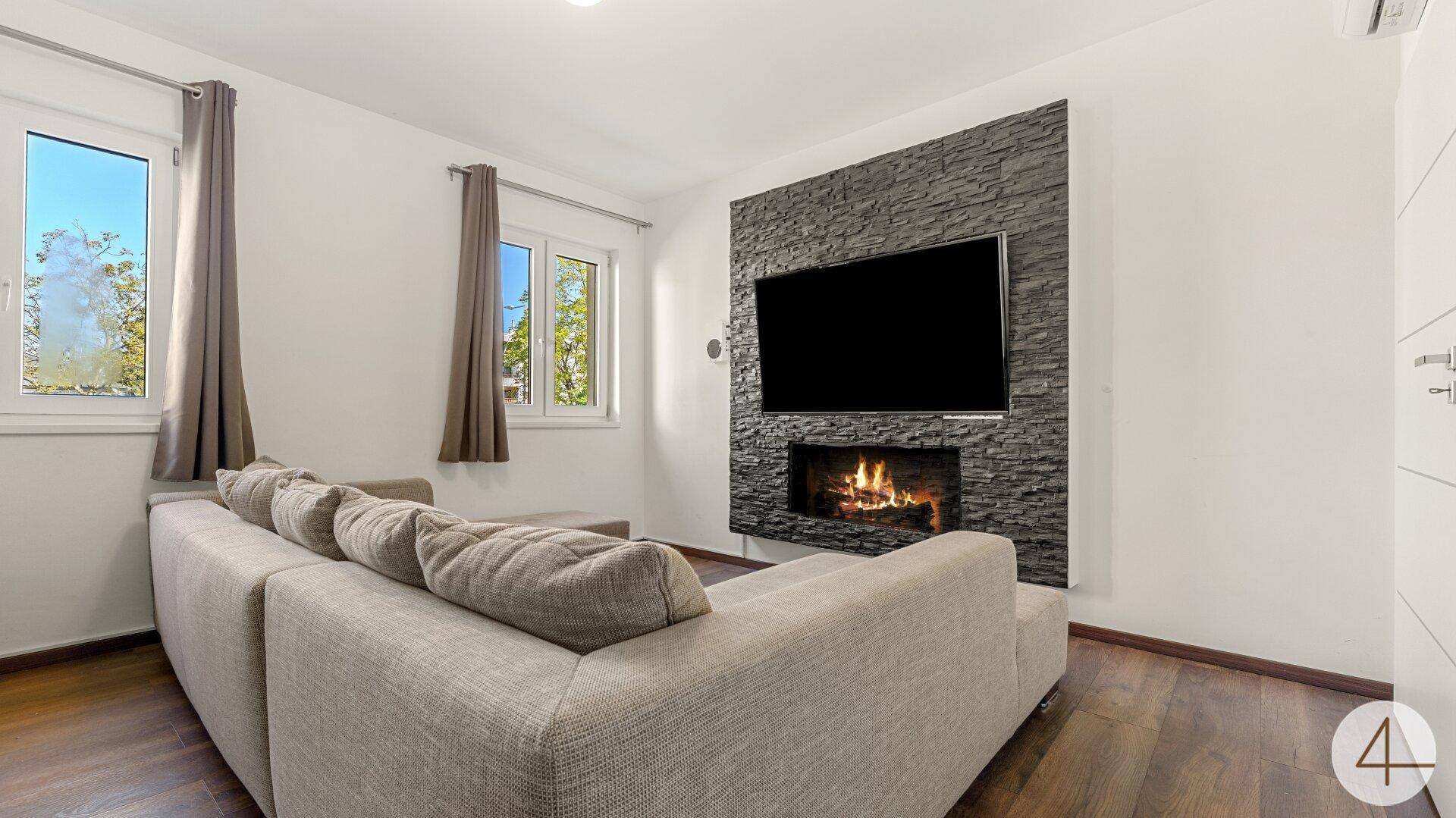 Modernes Wohnzimmer mit großem Ecksofa und Kaminwand mit integriertem Fernseher.