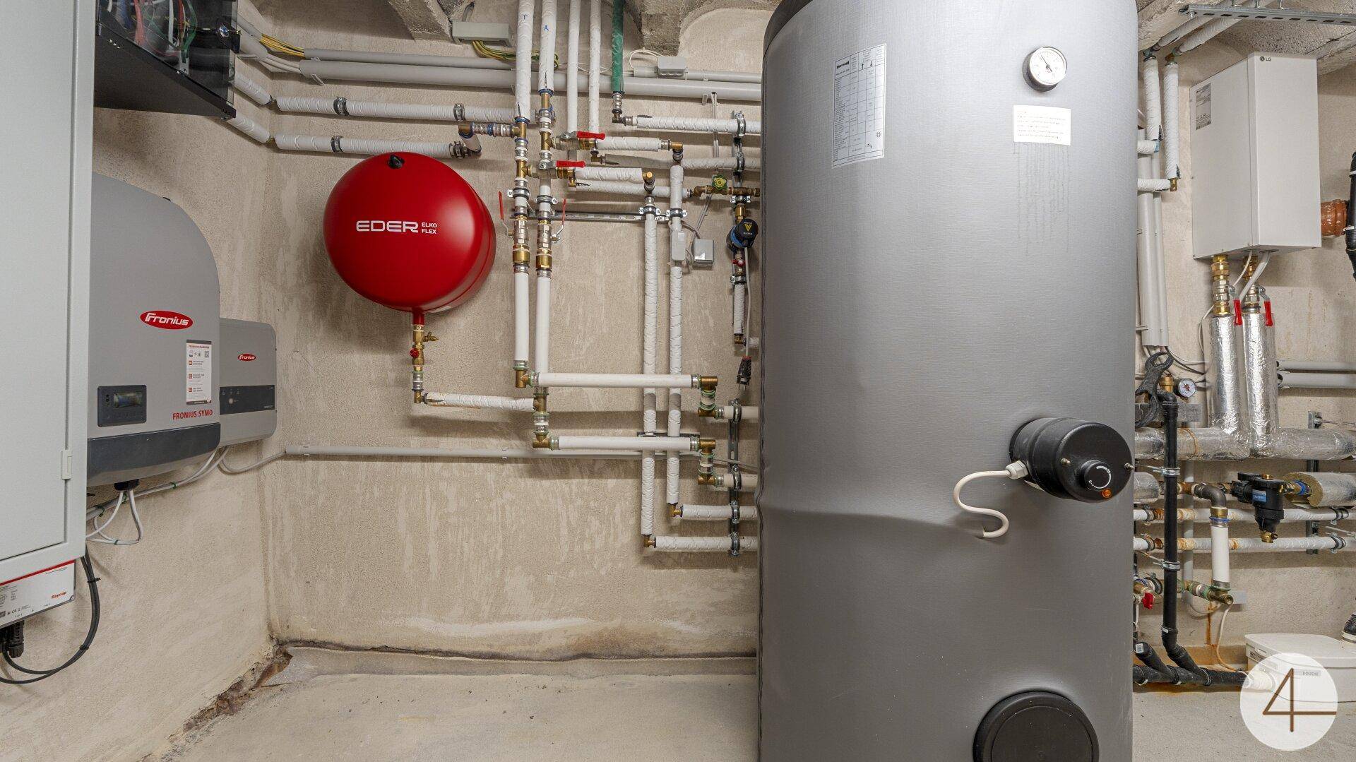 Technikraum im Untergeschoss mit Heizungsanlage, Warmwasserspeicher und Rohrleitungen.