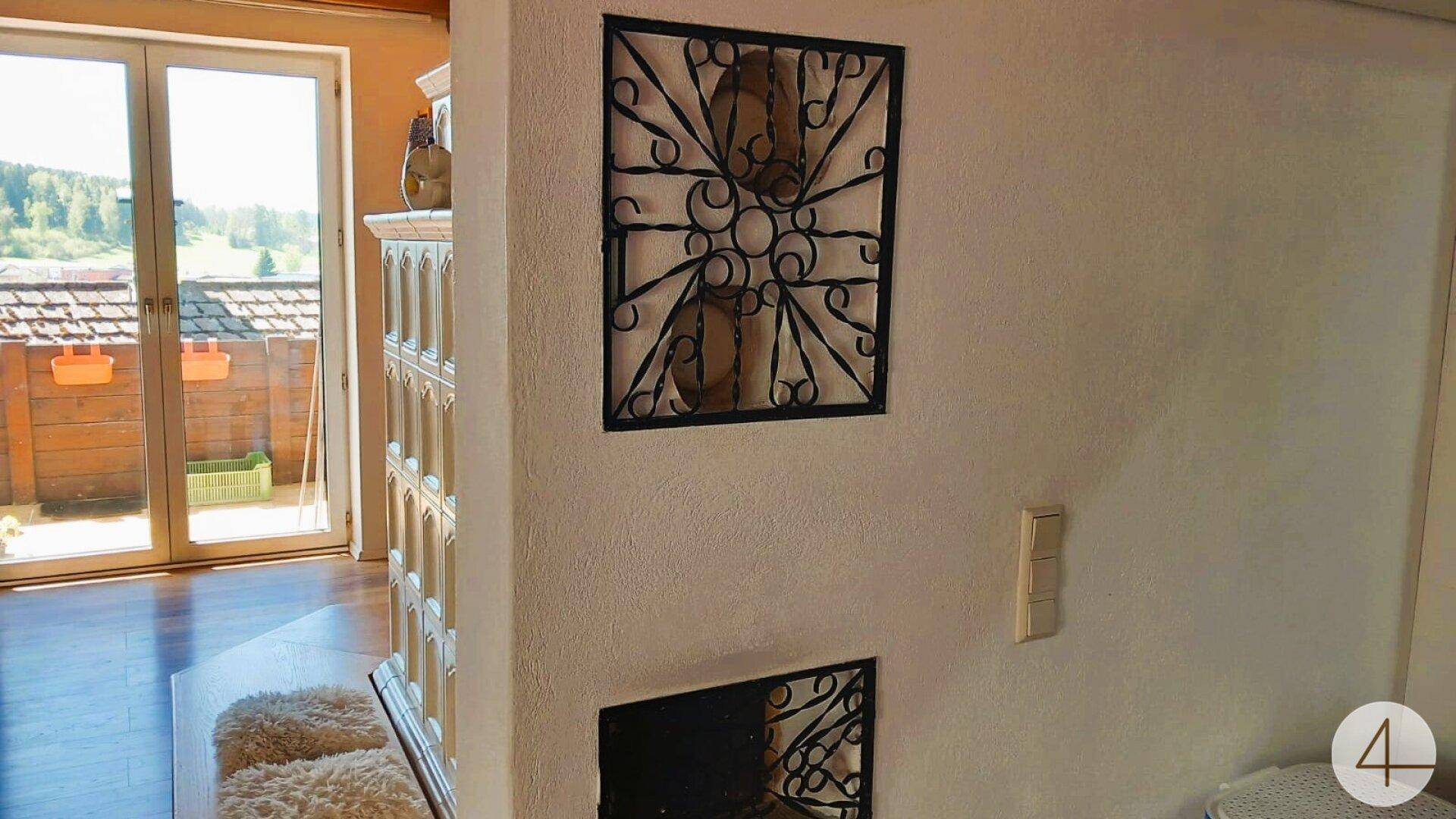 Helles Wohnzimmer mit traditionellem Kachelofen und direktem Zugang zu einem Balkon mit Weitblick.