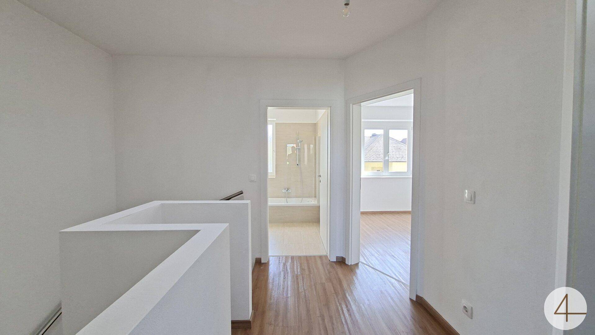 Obergeschossflur mit Laminatboden und Blick in das moderne Badezimmer.