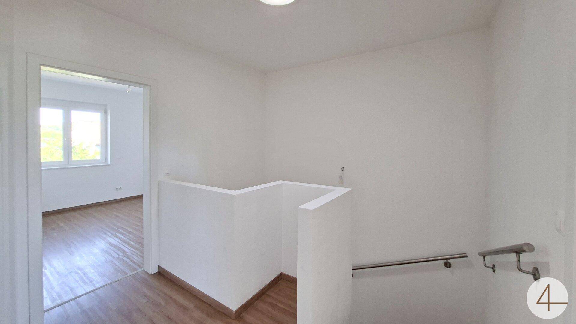 Heller Flur im Obergeschoss mit Laminatboden und Blick in angrenzende Zimmer.