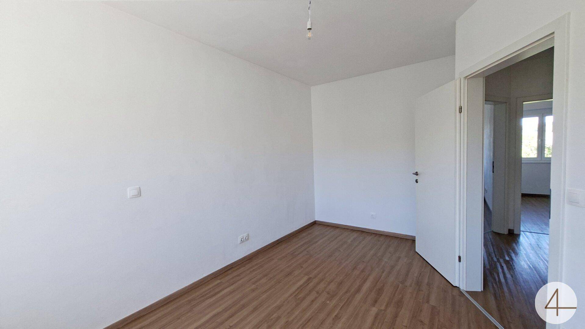 Geräumiges Schlafzimmer mit Laminatboden und weiß gestrichenen Wänden.