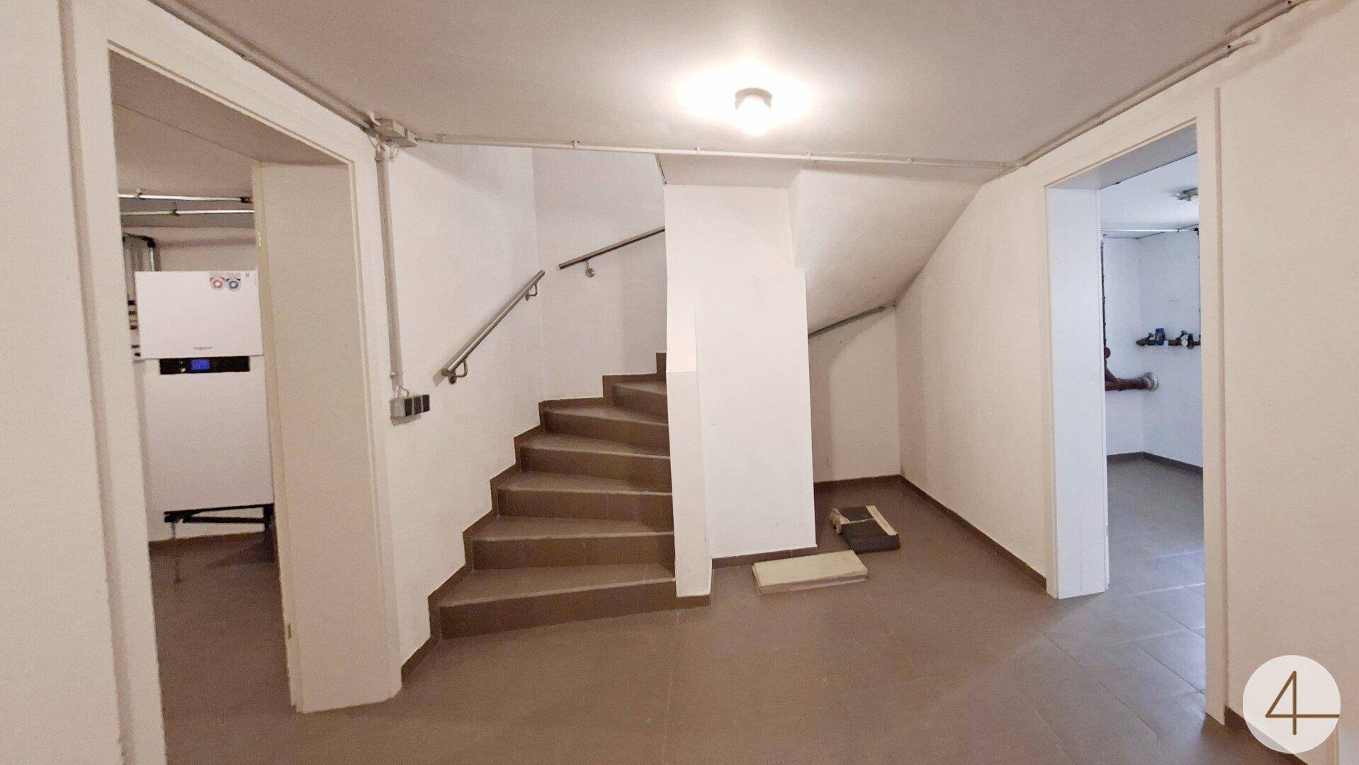 Kellerbereich mit Heizungsanlage, gefliestem Boden und Treppenaufgang.