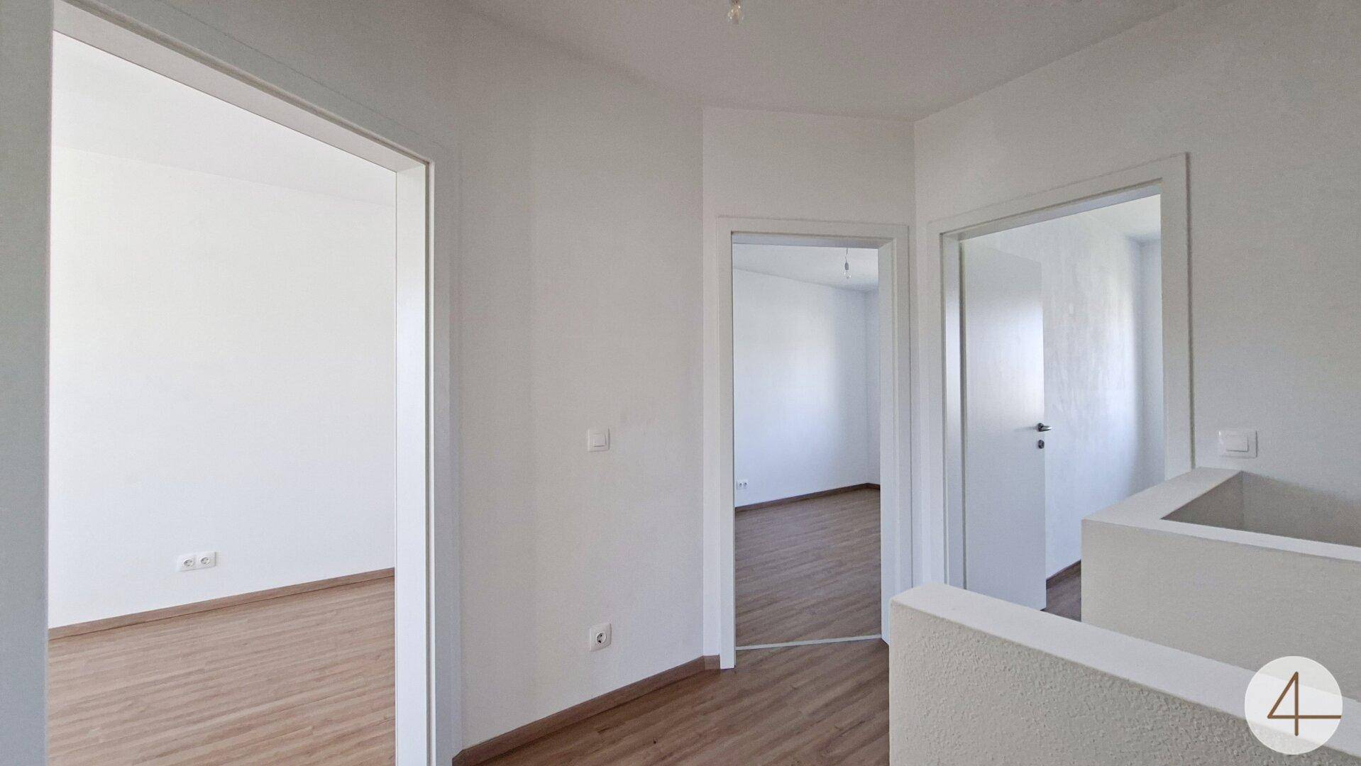 Geräumiger Flur im Obergeschoss mit Laminatboden und Zugang zu mehreren Räumen.