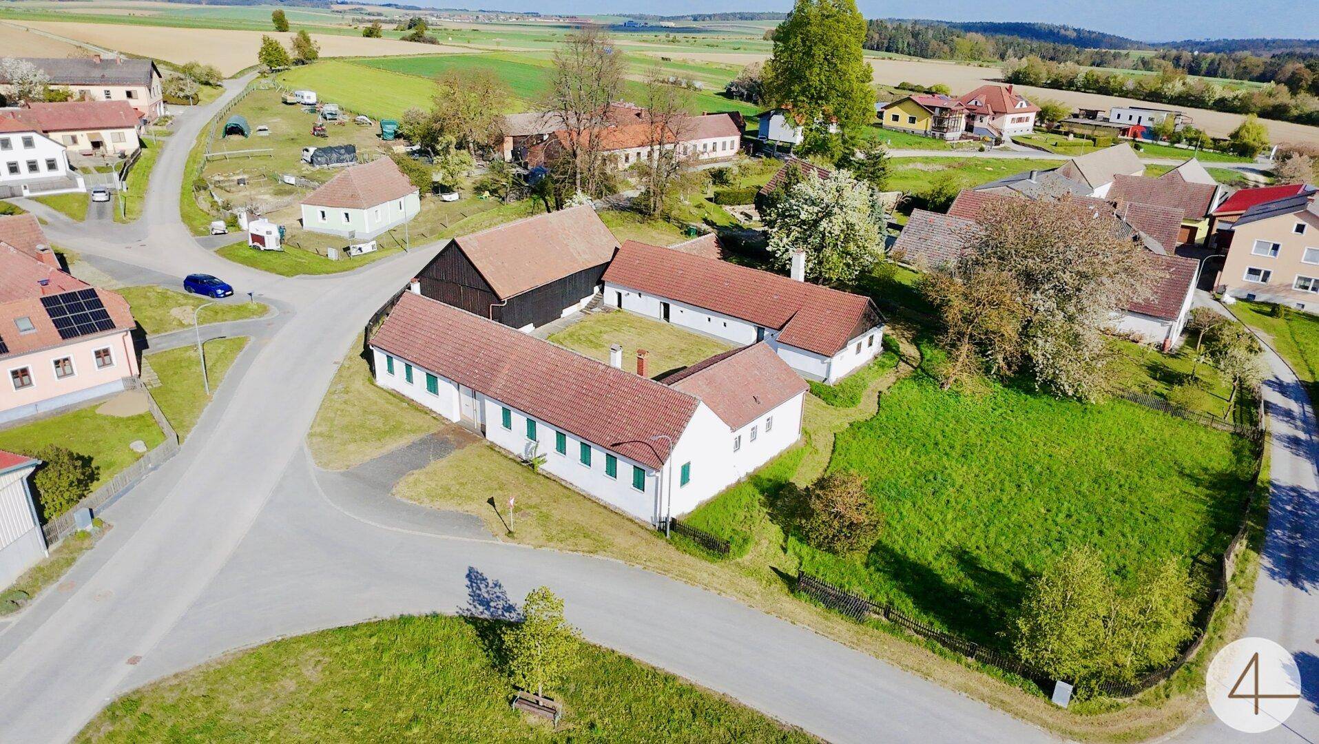 Weitläufiges ländliches Anwesen mit traditionellen Gebäuden, umgeben von grünen Wiesen und Feldern.