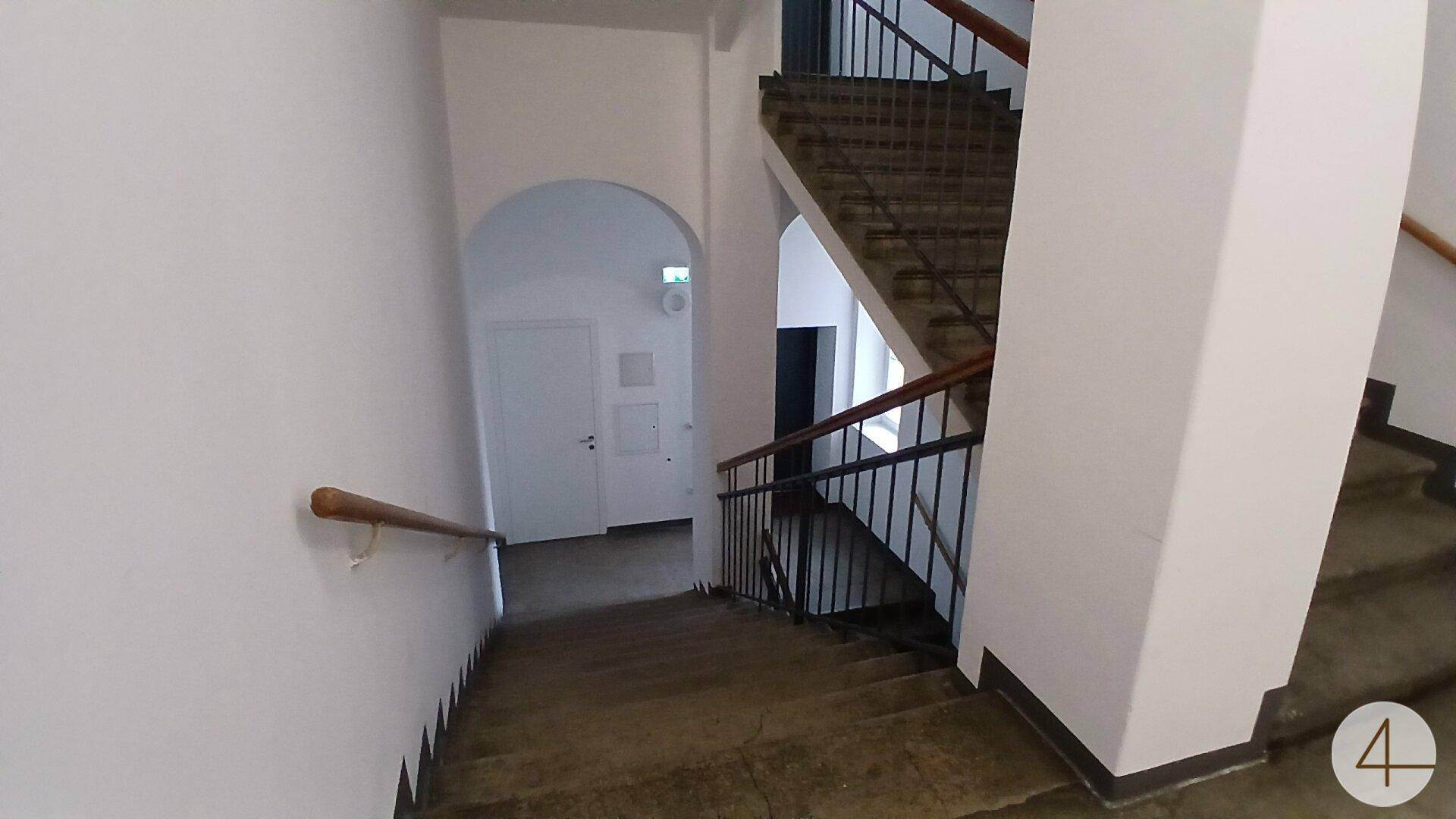 Geräumiges Treppenhaus mit Holzgeländer und Blick auf die verschiedenen Etagen.