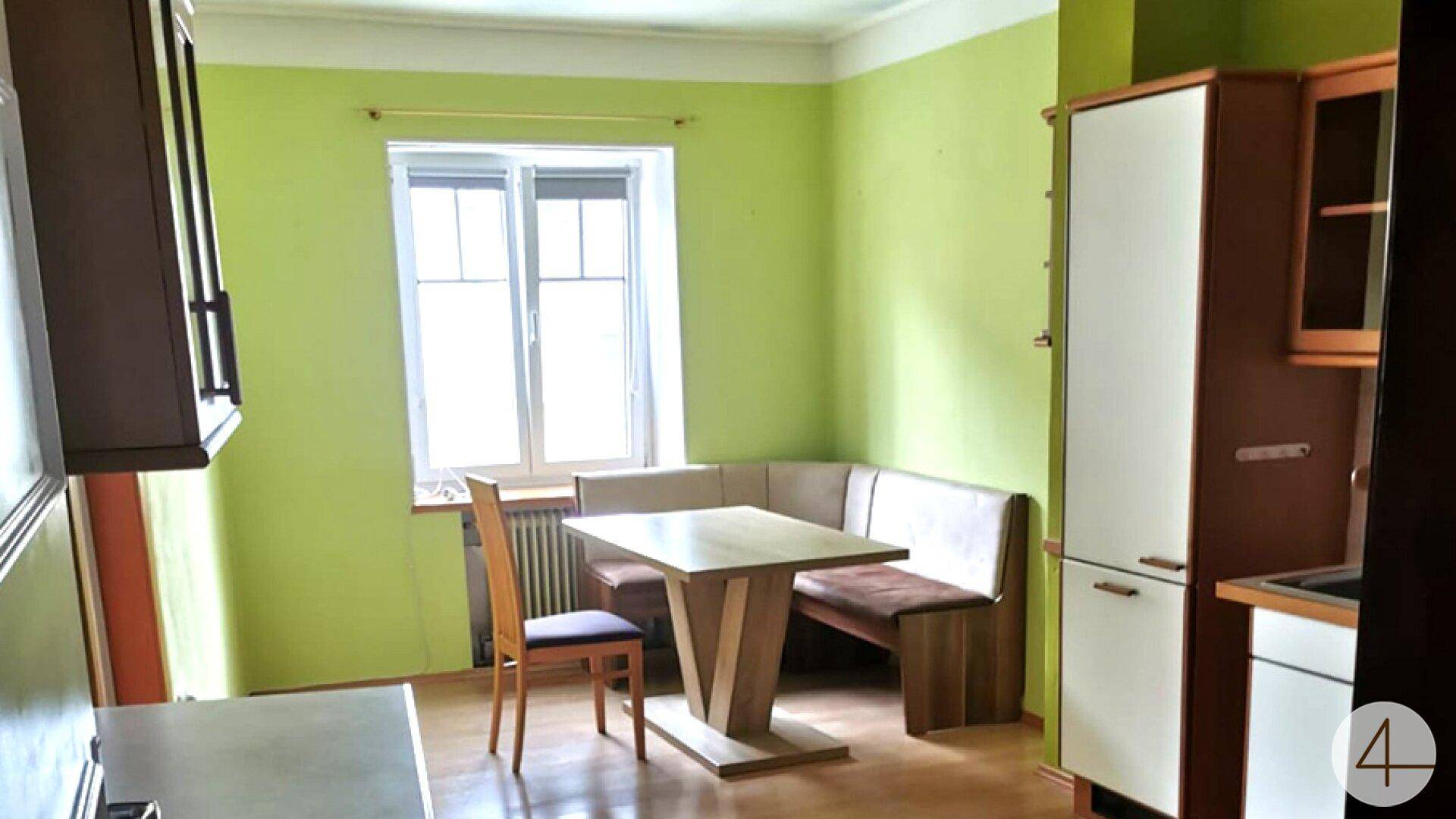 Gemütliche Küche mit lindgrünen Wänden, einer Essecke und Holzschränken für Stauraum.