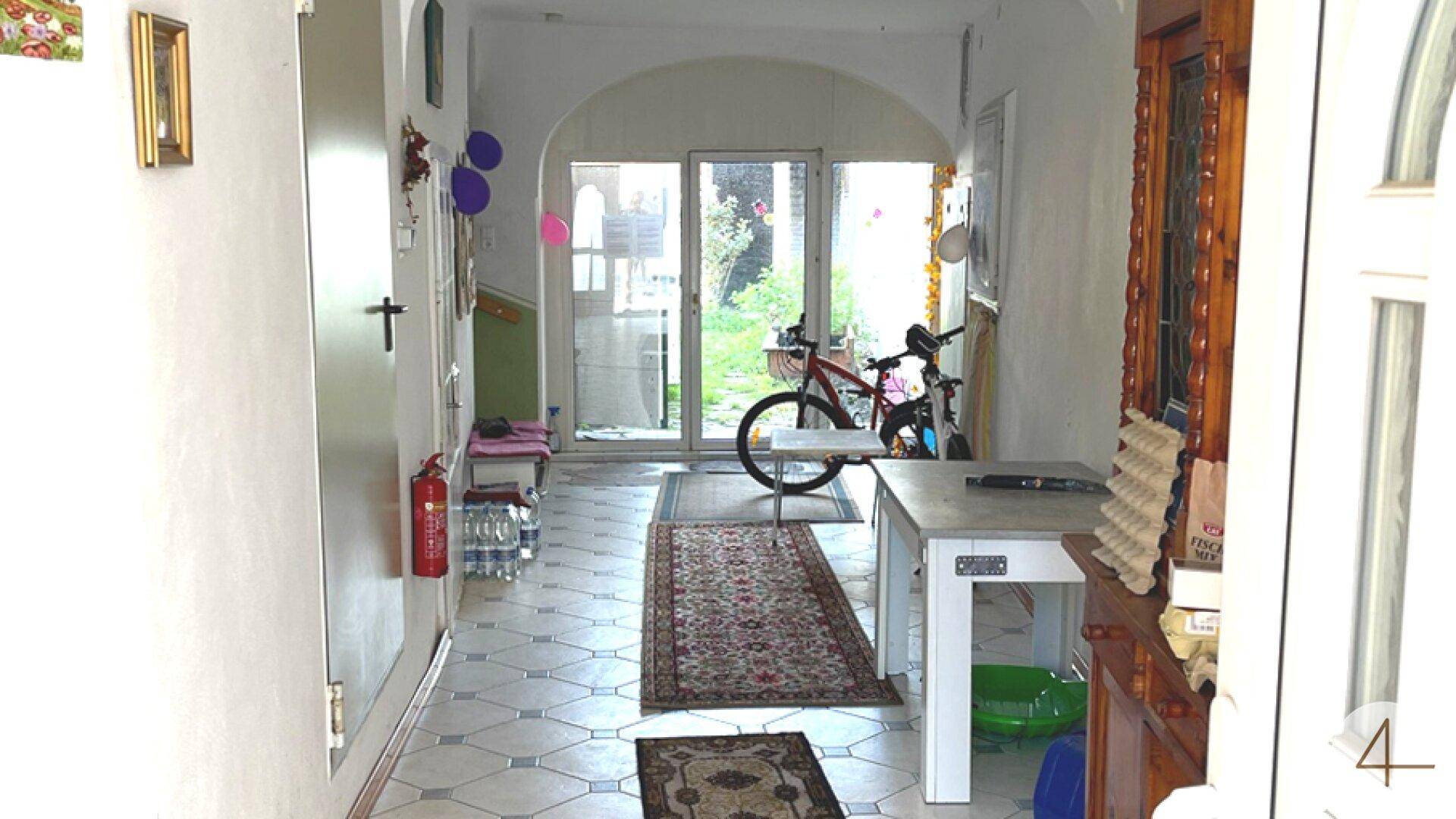 Heller Eingangsbereich mit gemusterten Fliesen, einem Fahrrad und Blick in den Garten.