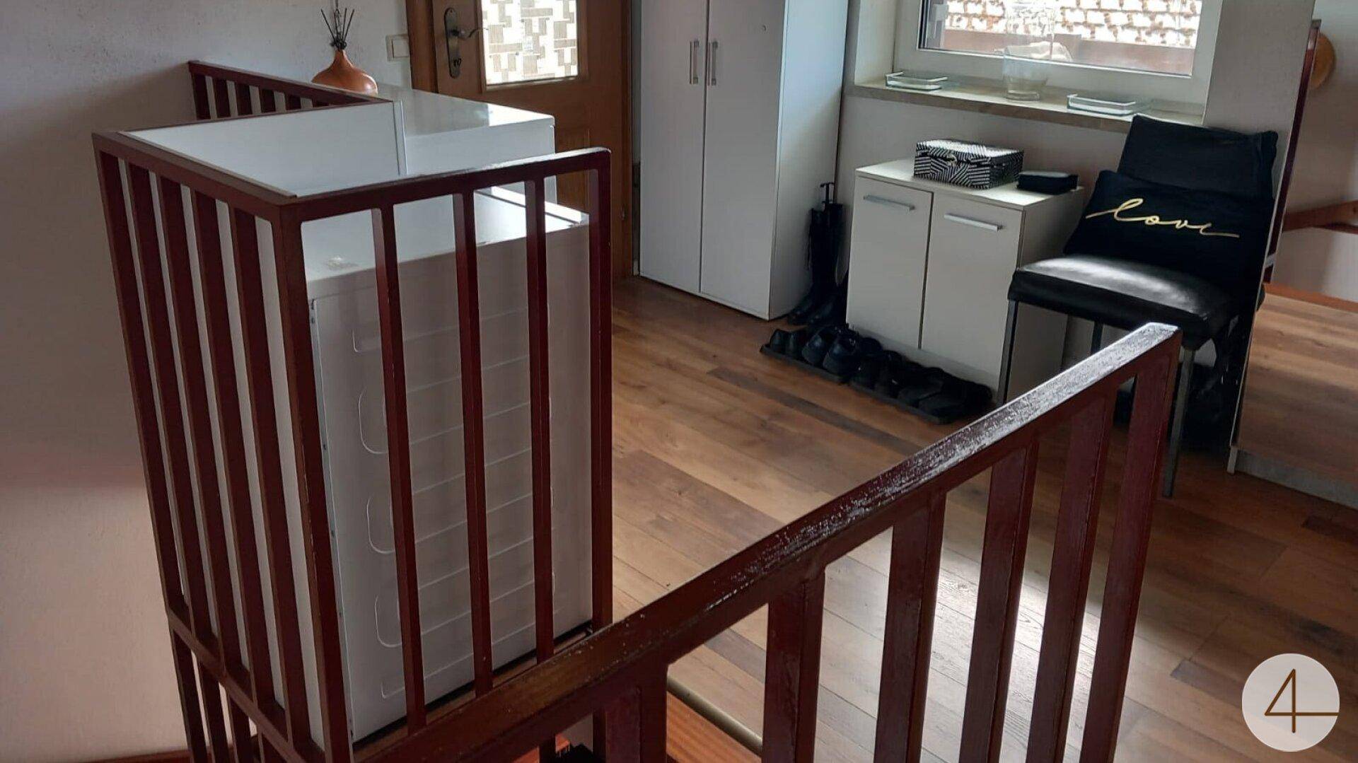 Heller Flurbereich mit Holzfußboden, Waschmaschine und Zugang zu weiteren Räumen.