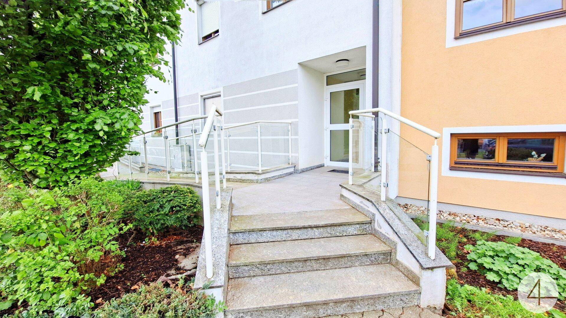 Eingangsbereich des Gebäudes mit Treppe und barrierefreier Rampe.