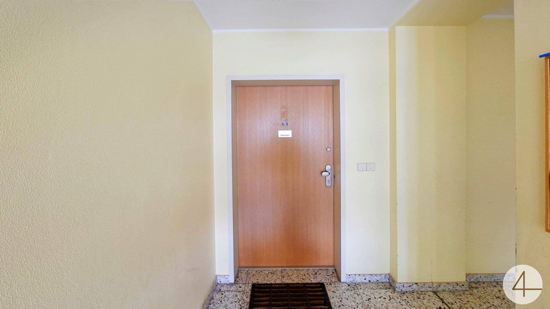 Eingangsbereich der Wohnung mit Holztür und gefliestem Boden.