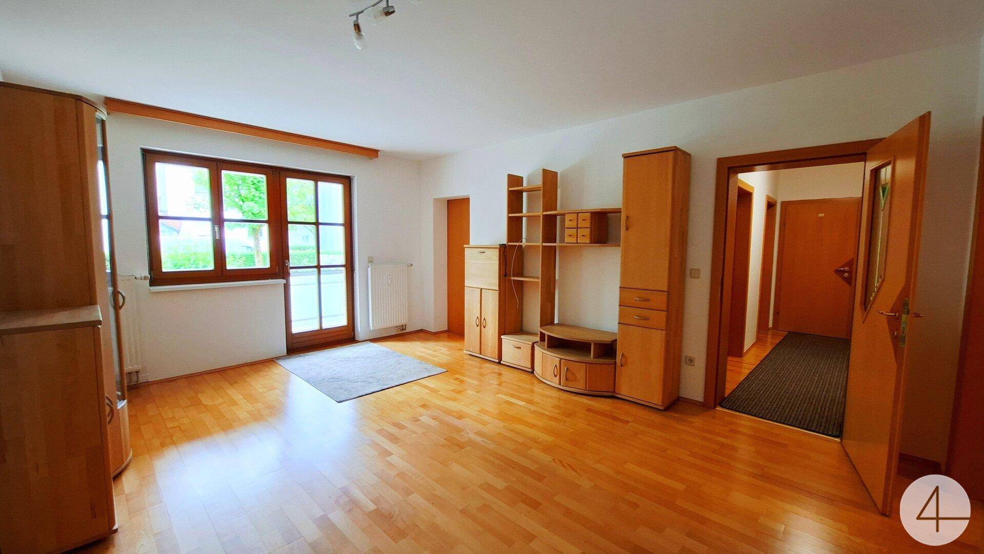 Helles Wohnzimmer mit Holzparkettboden, großen Fenstern und Holzmöbeln.