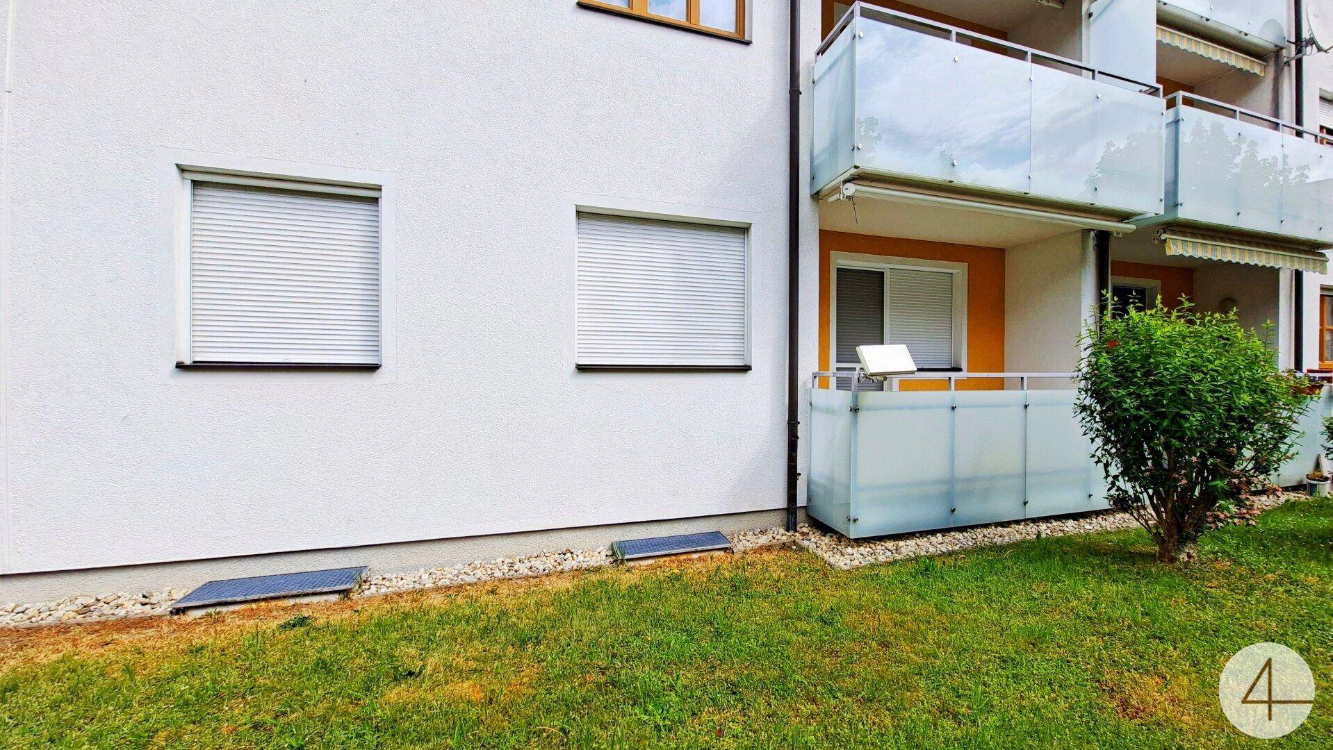 Balkon mit geschlossenen Rollläden und Glasbrüstung am Gebäude.