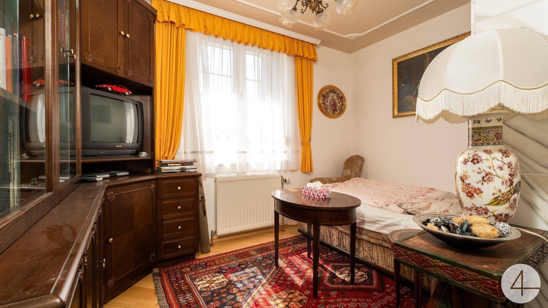 Gemütliches Schlafzimmer mit Einzelbett, Holzmöbeln und einem traditionellen Teppich.