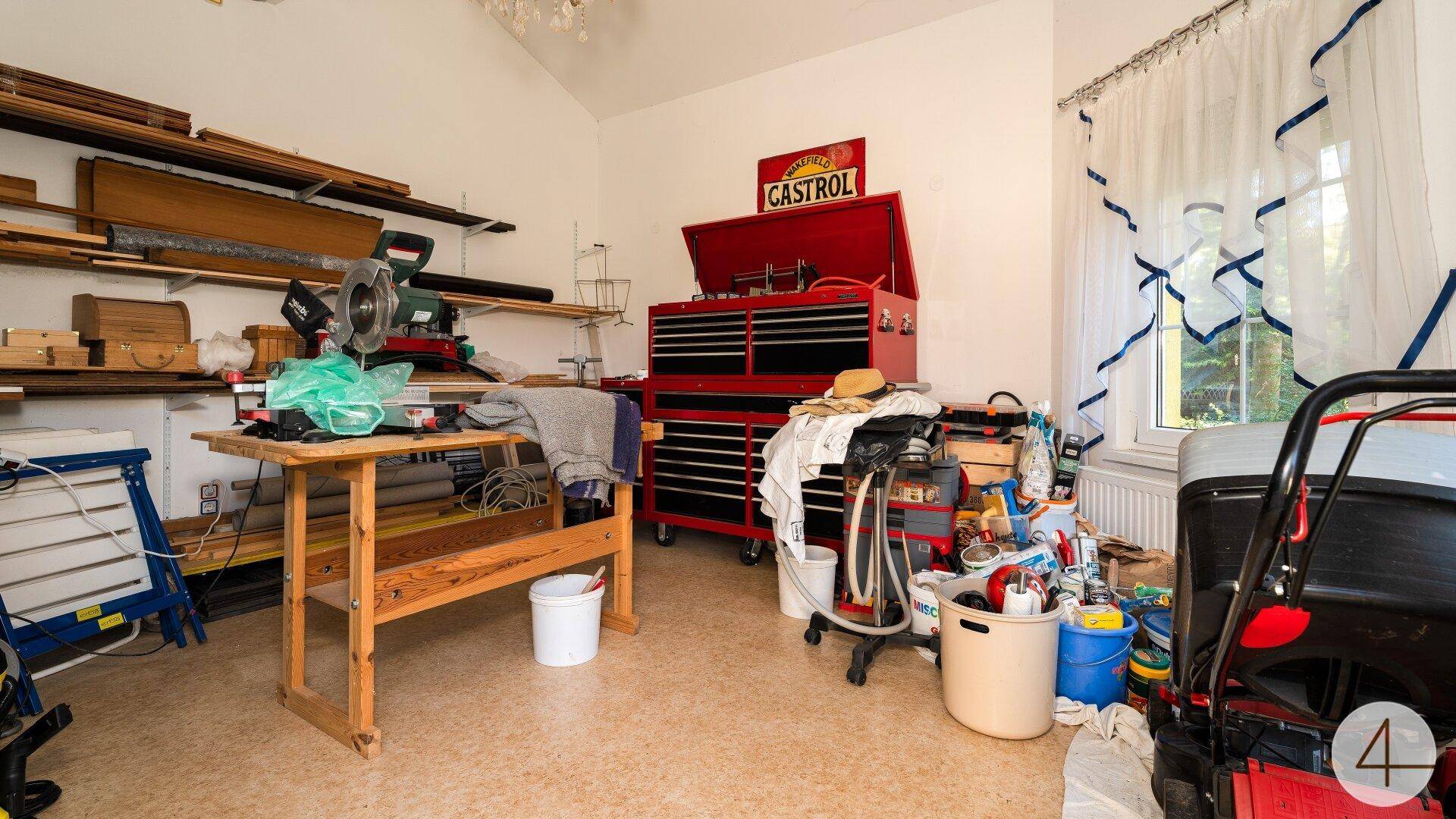 Geräumige Werkstatt mit vielen Werkzeugen, Regalen und einem großen roten Werkzeugschrank.
