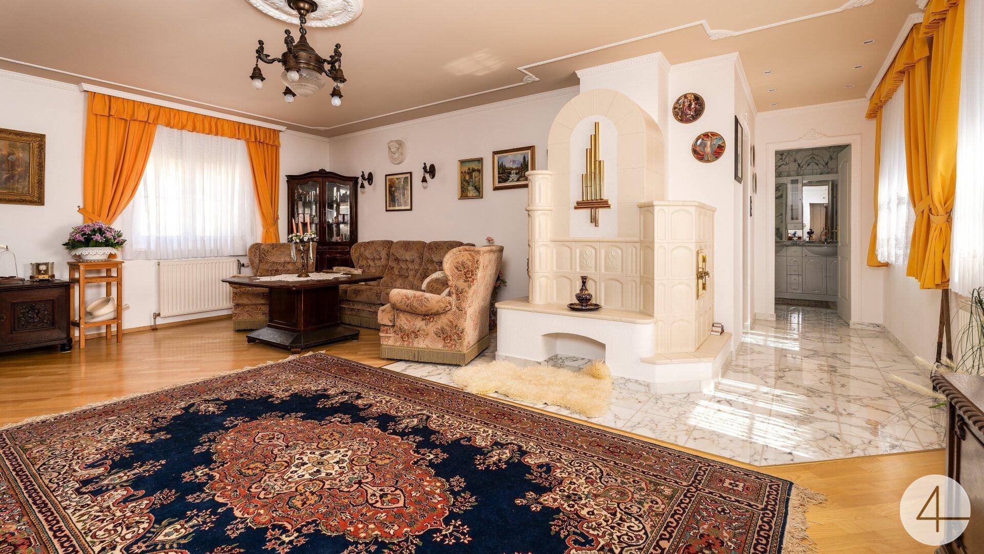 Gemütliches Wohnzimmer mit traditionellem Kachelofen, Parkettboden und einem orientalischen Teppich.