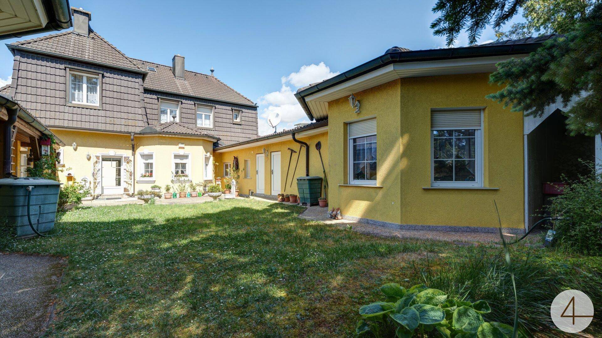 Gepflegter Innenhof mit Rasen und gelben Gebäudefassaden, die eine gemütliche Atmosphäre schaffen.